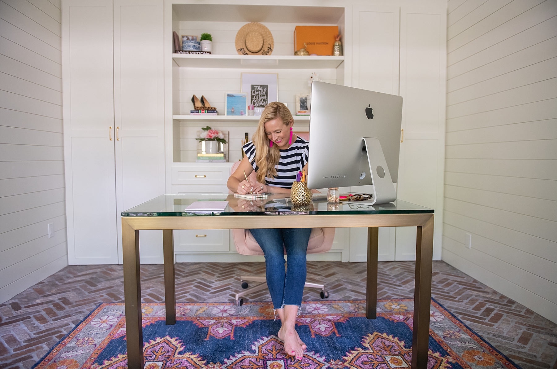 Work From Home Essentials by popular Houston lifestyle blog, Fancy Ashley: image of a woman sitting at a glass top and gold leg desk in front of a Apple desktop computer. 