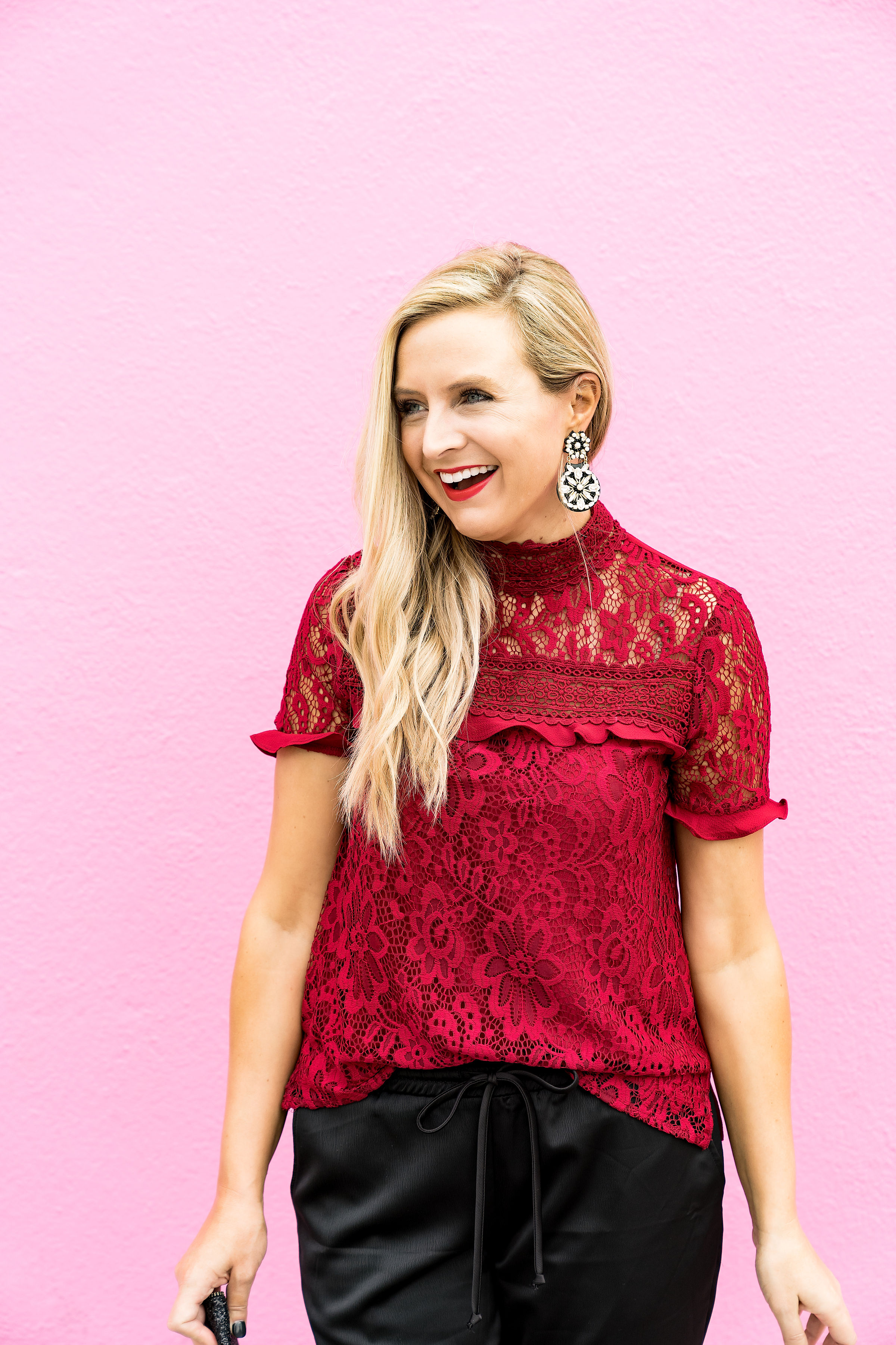 Top Houston fashion blogger, Fancy Ashley, features 7 Holiday Outfits perfect for the season: image of a woman wearing red lace top, black jogger pants, Kate Spade earrings, glitter clutch and sam Edelman leopard pumps all available at Nordstrom