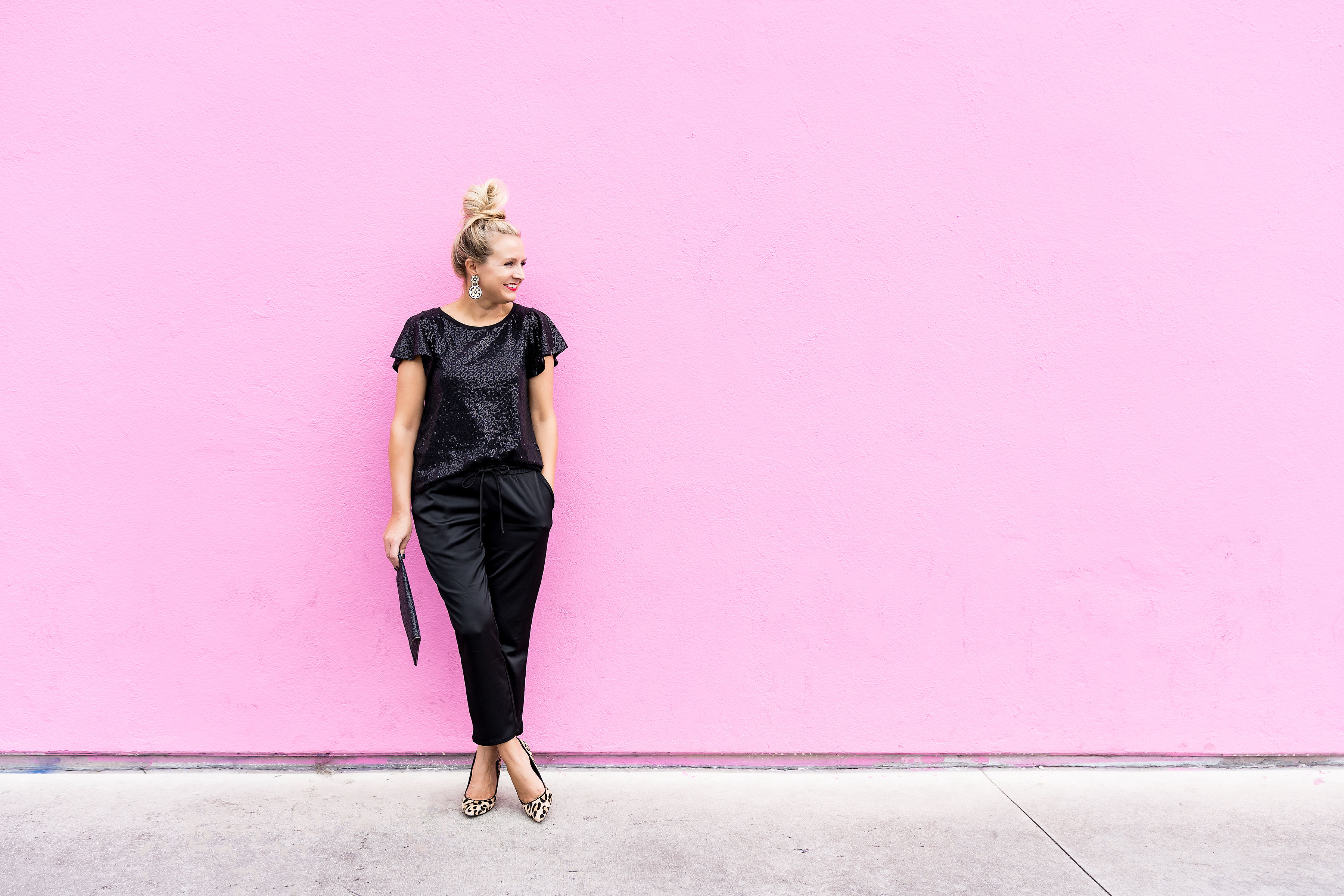 Gibson x Glam Collection Outfits featured by top Houston fashion blog, Fancy Ashley: a blonde woman stood against a wall wearing gibson x glam black sequin tops and silk joggers
