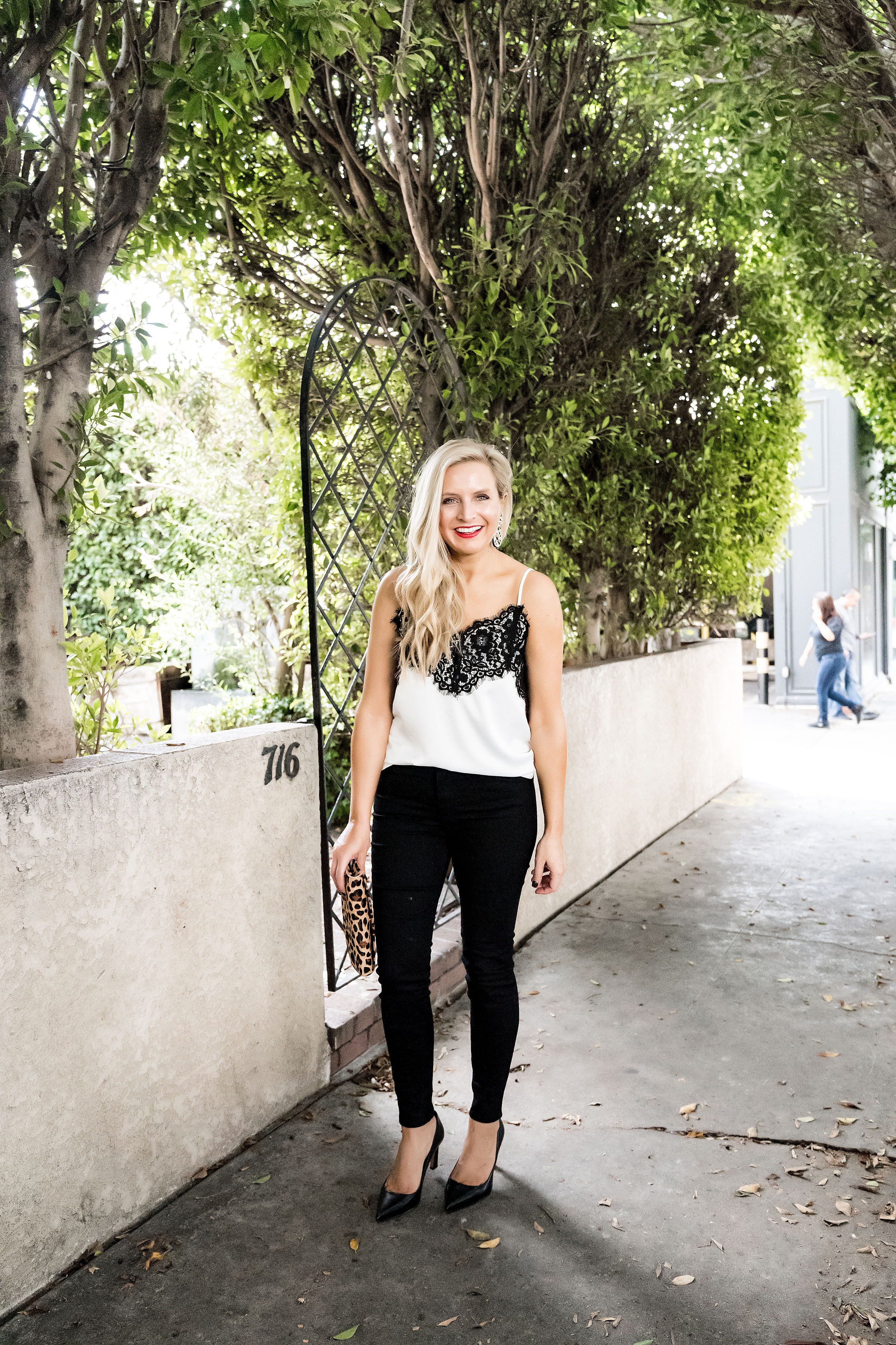 Gibson x Glam Collection Outfits featured by top Houston fashion blog, Fancy Ashley: a blonde woman walking wearing lace camisole, black denim jeans, black heels, leopard clutch