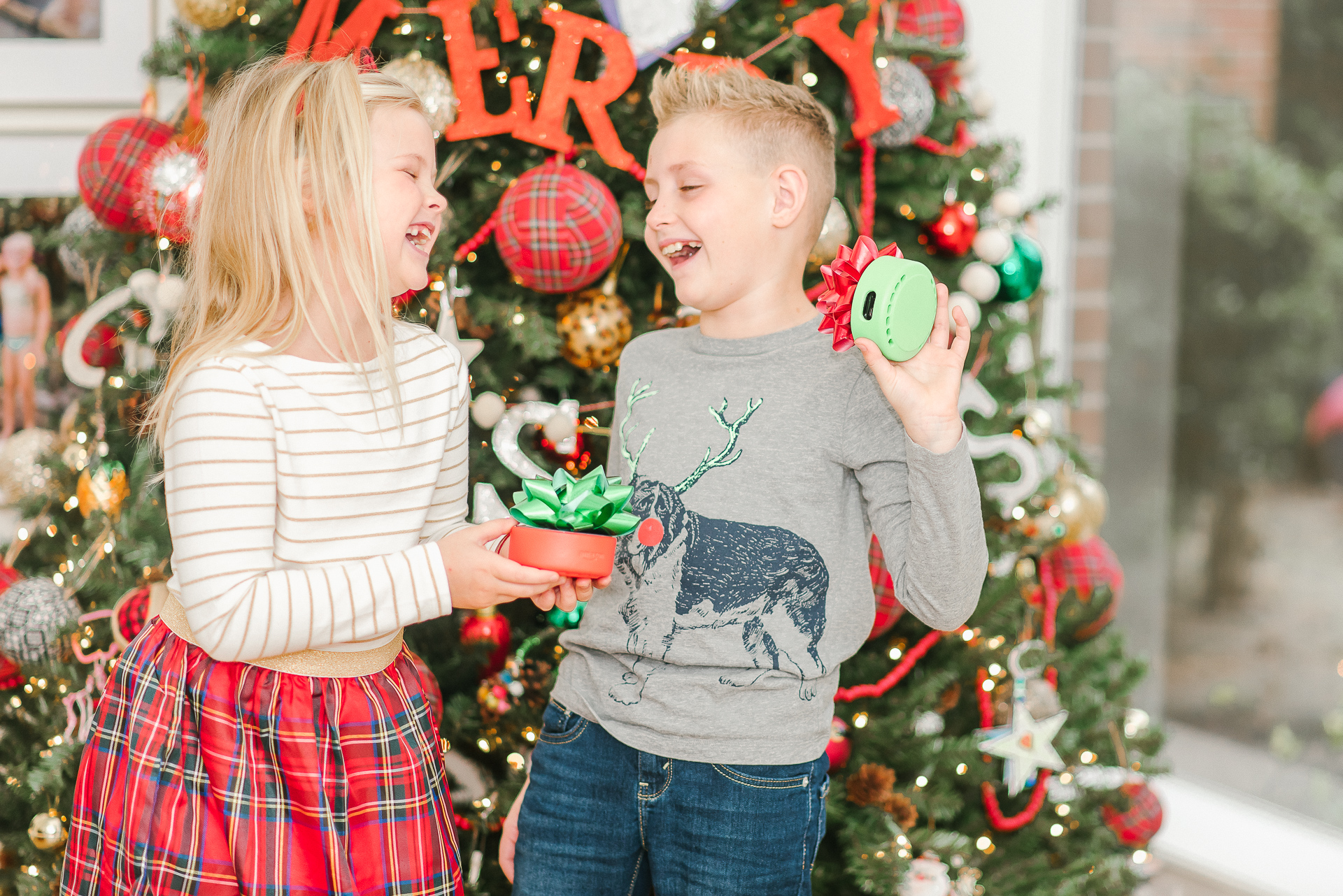 Echo Dot Kids Edition review featured by top Houston lifestyle blogger, Fancy Ashley: image of siblings holding wrapped Amazon Echos Kids Edition