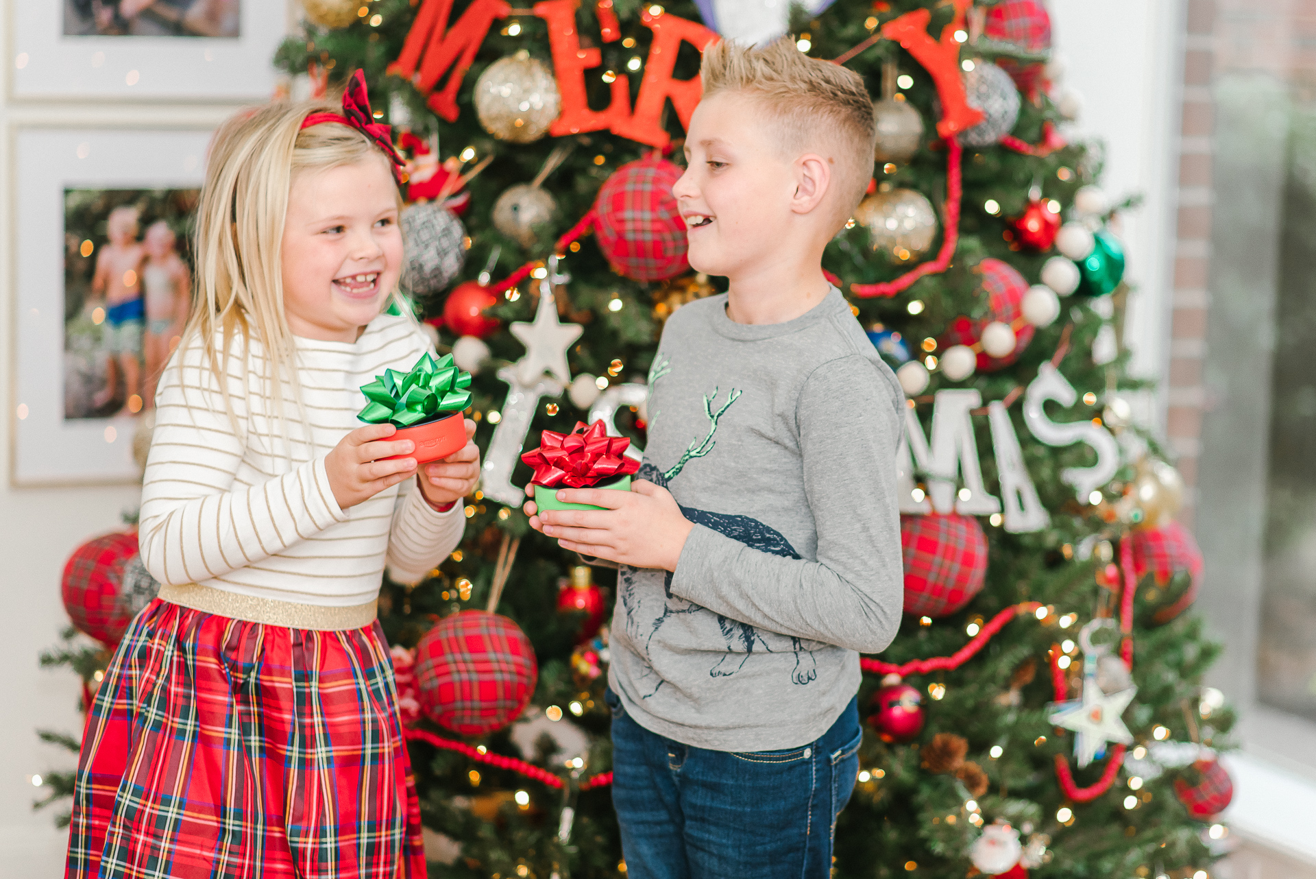 Echo Dot Kids Edition review featured by top Houston lifestyle blogger, Fancy Ashley: image of siblings holding wrapped Amazon Echos Kids Edition