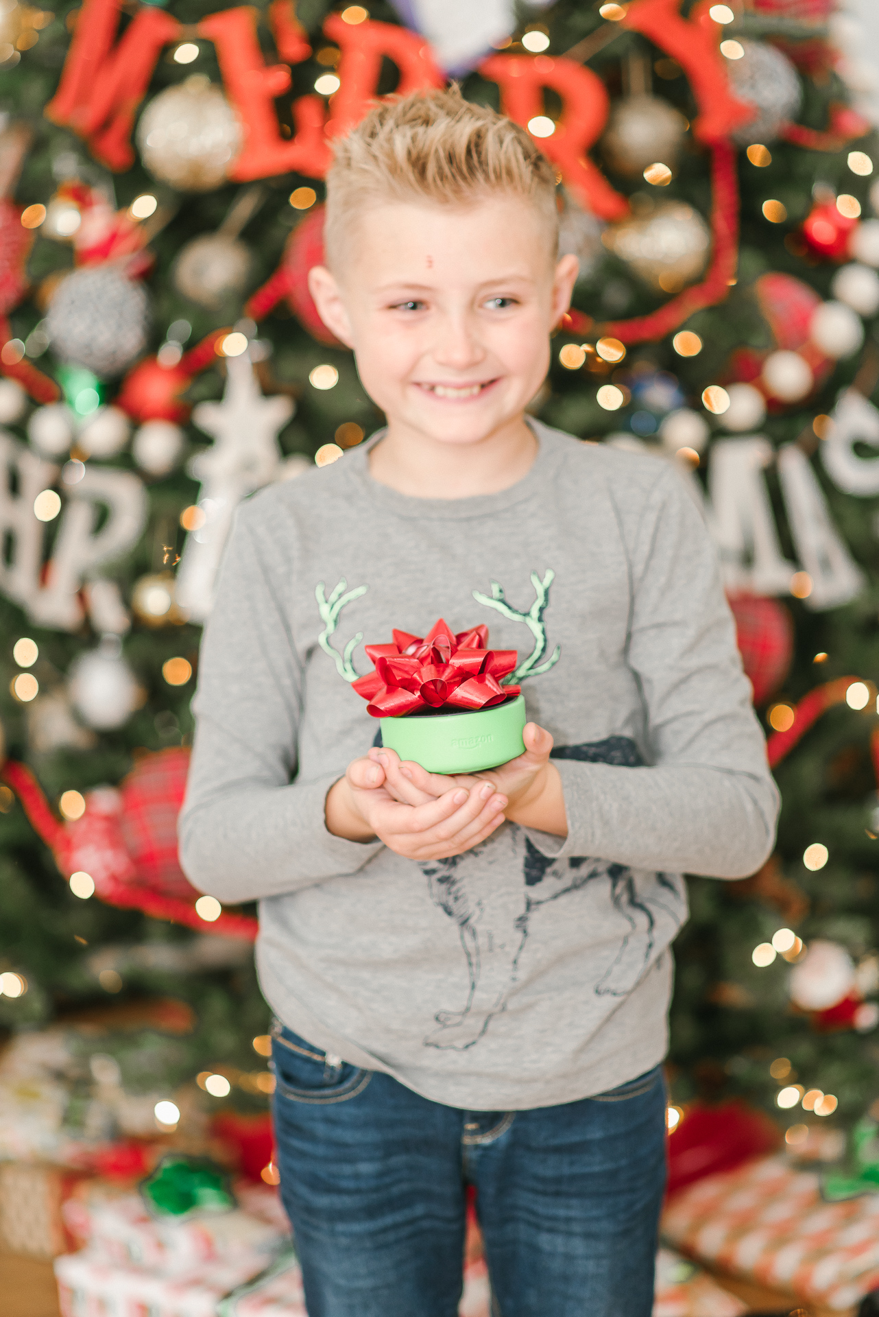 Echo Dot Kids Edition review featured by top Houston lifestyle blogger, Fancy Ashley: image of a boy holding a wrapped Amazon Echo Kids Edition