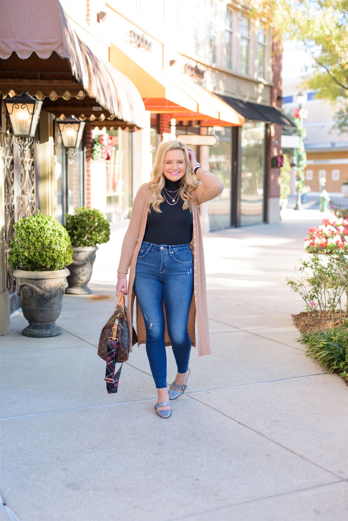 December Outfits by popular Houston fashion blog, Fancy Ashley: image of a woman standing outside and wearing a black turtleneck shirt, tan long line cardigan, jeans, and sliver slide flats while holding a Louis Vuitton bag.  