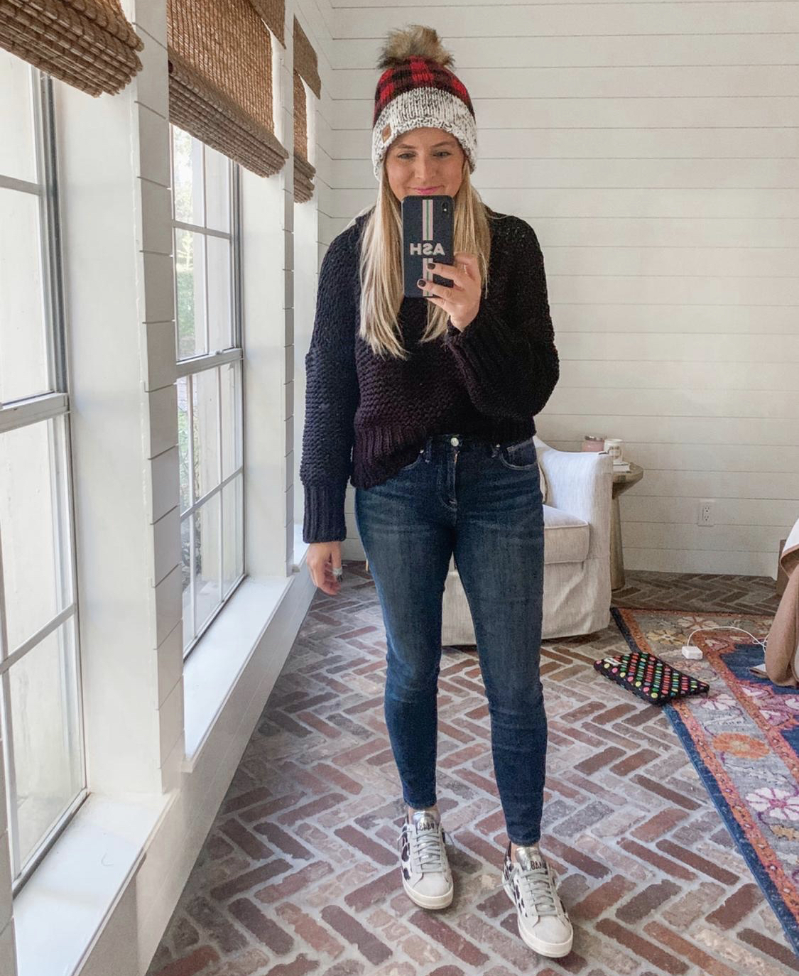 December Outfits by popular Houston fashion blog, Fancy Ashley: image of a woman a black and red buffalo plaid beanie, black cable knit sweater, jeans, and leopard print golden goose sneakers. 