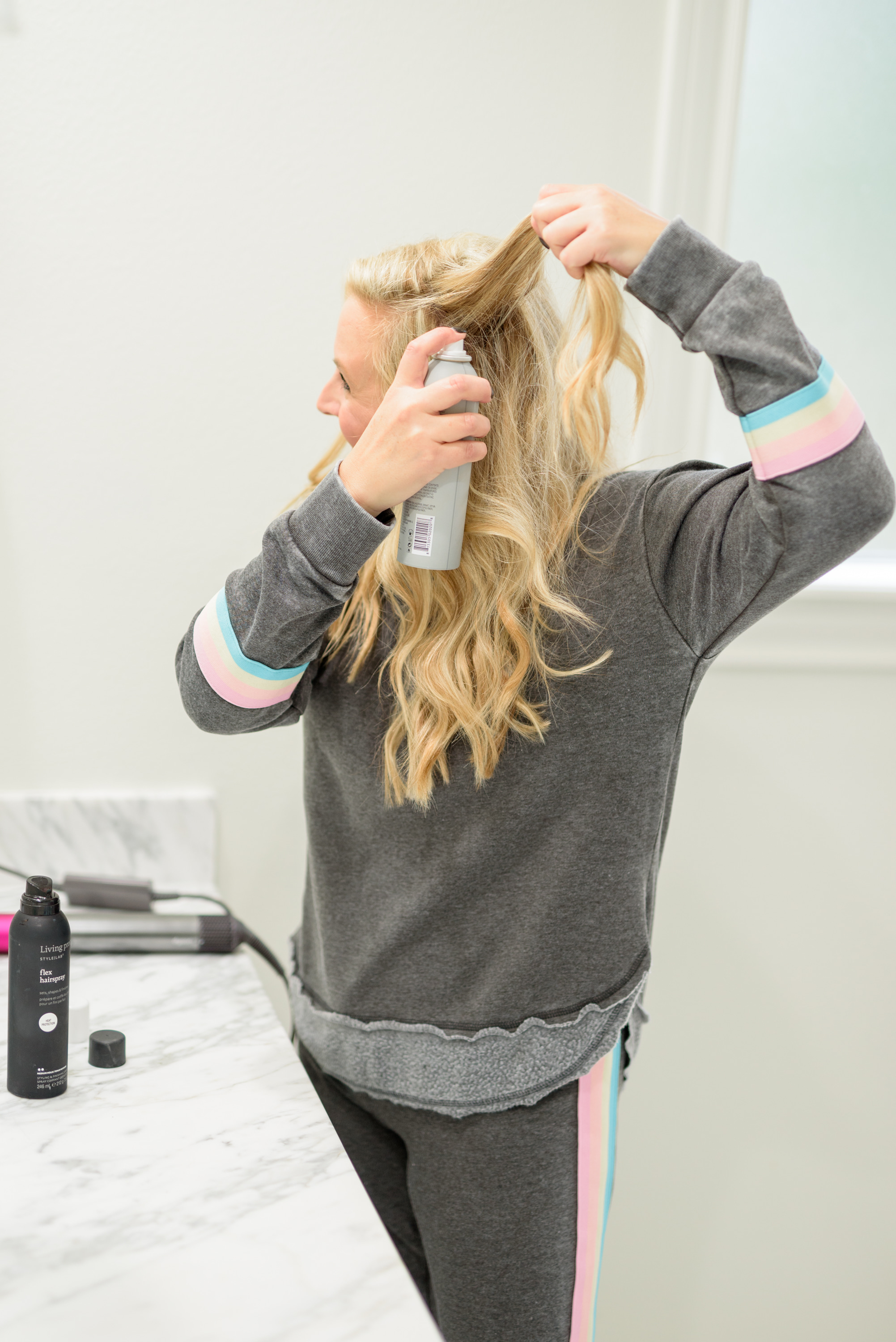 Fall Beauty by popular Houston beauty blog, Fancy Ashley: image of a woman sitting on her bathroom vanity and wearing a Burnout Stripe Sweatshirt VINTAGE HAVANA and Burnout Stripe Joggers VINTAGE HAVANA and using Living Proof dry shampoo.