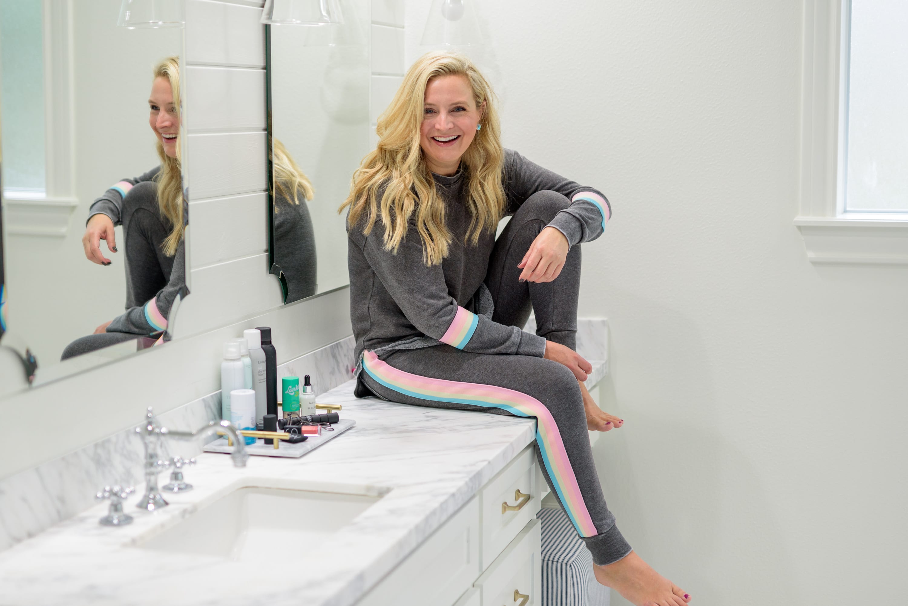 Fall Beauty by popular Houston beauty blog, Fancy Ashley: image of a woman sitting on her bathroom vanity and wearing a Burnout Stripe Sweatshirt VINTAGE HAVANA and Burnout Stripe Joggers VINTAGE HAVANA.