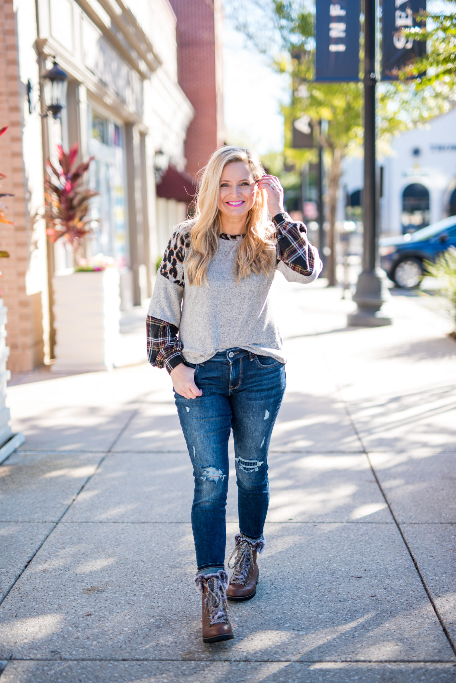 Maurice's Clothing by popular Houston fashion blog, Fancy Ashley: image of a woman wearing a Maurice's 24/7 Leopard Plaid Colorblock Blouson Sleeve Baseball Tee, distressed denim, and brown fur trimmed combat boots. 