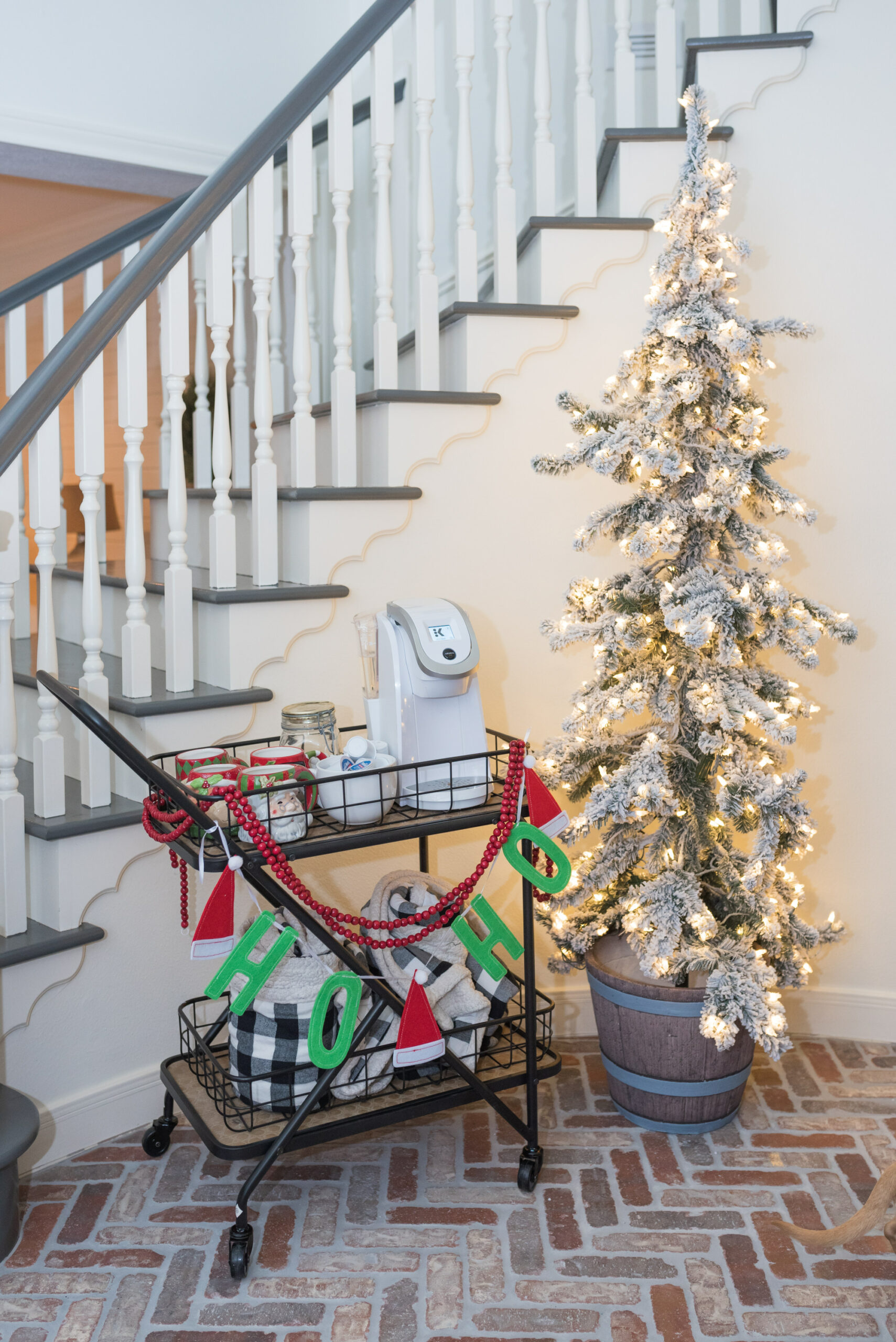 Hot Cocoa Bar by popular Houston lifestyle blog, Fancy Ashley: image of a black metal bar cart containing a Keurig, Santa mugs, Christmas garland, mini marshmallows, and coco pods. 