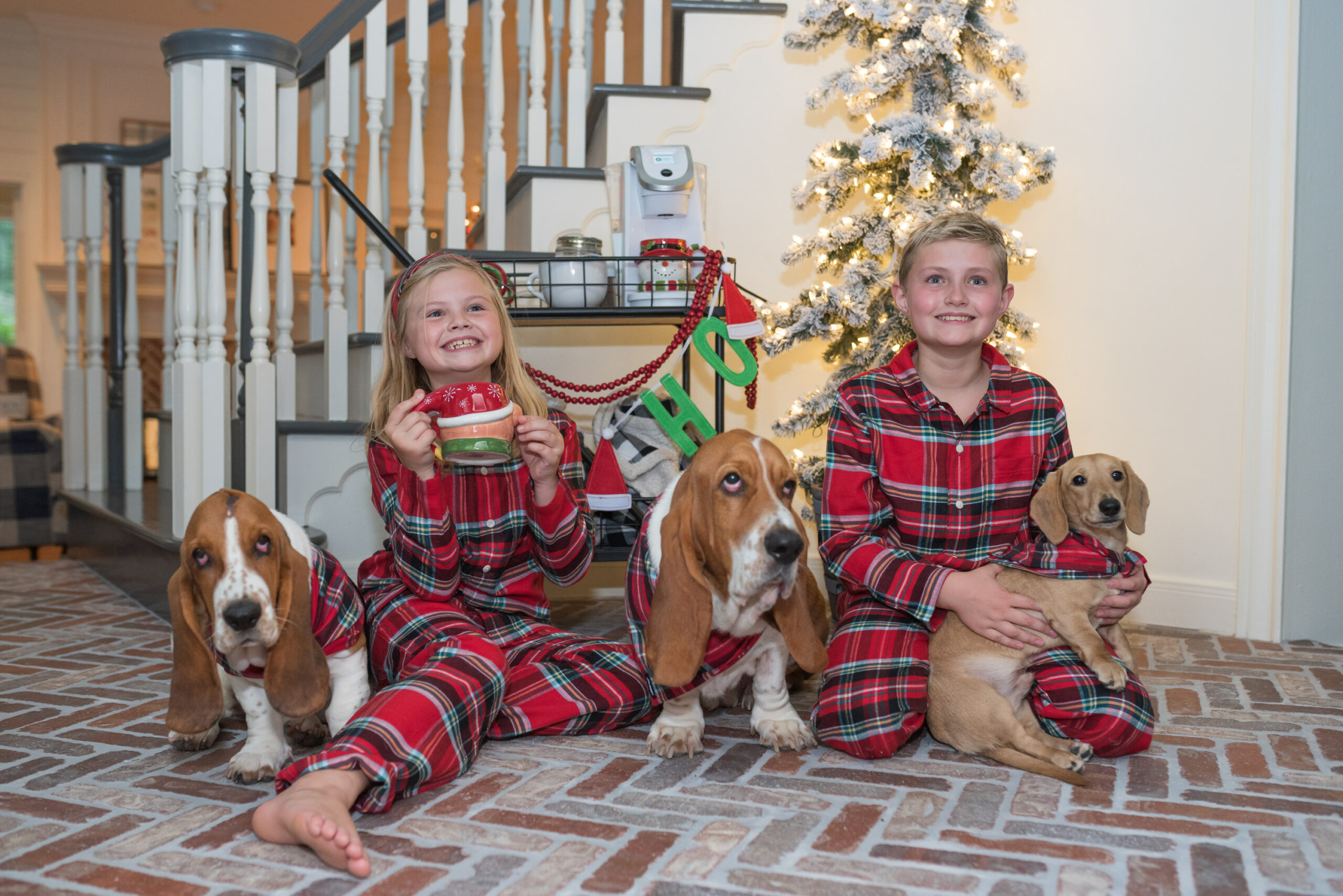 Family Christmas Pajamas by popular Houston fashion blog, Fancy Ashley: image of a young boy and girl sitting on the floor with their three dogs and wearing matching Land's End red plaid pajamas. 