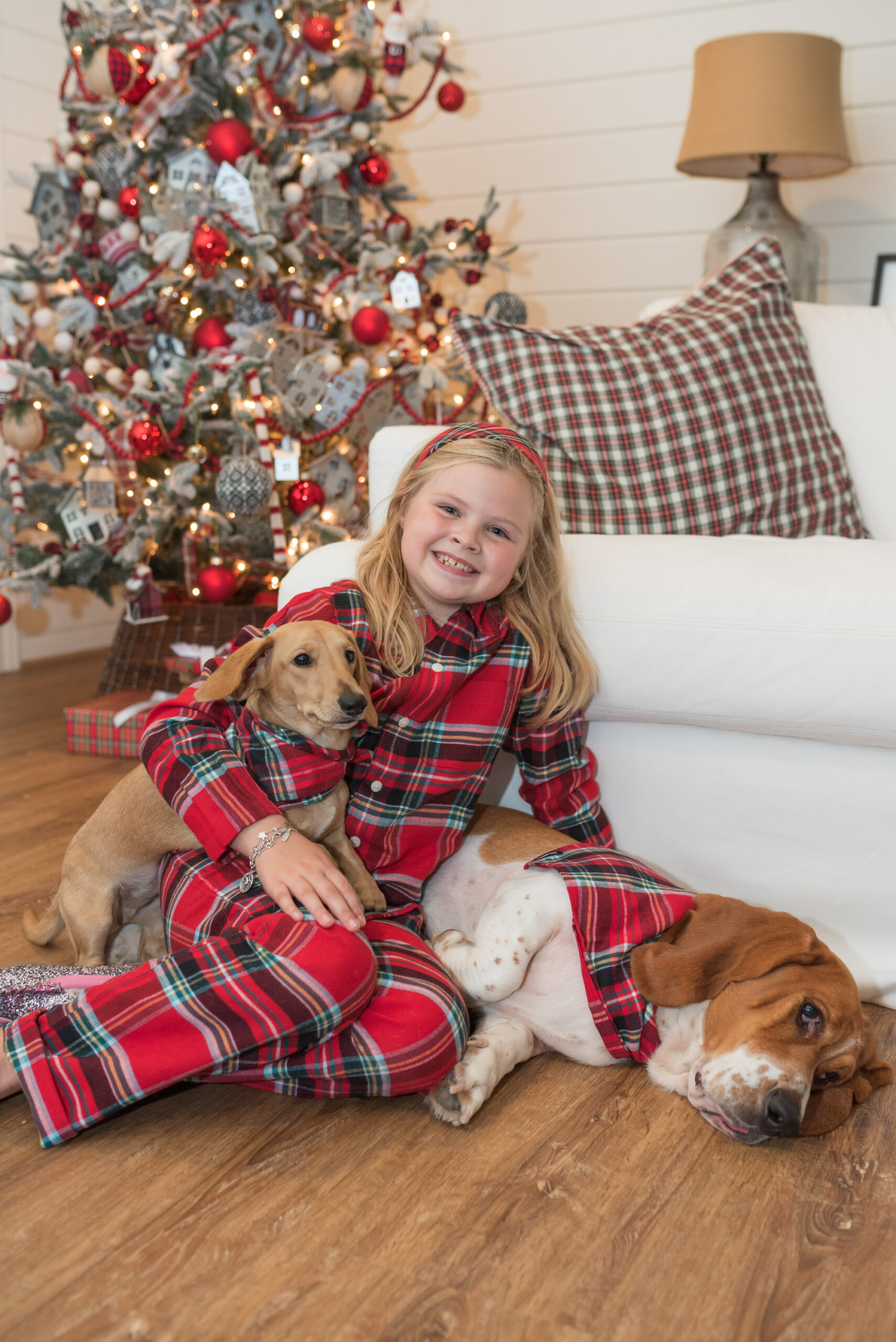 Family Christmas Pajamas by popular Houston fashion blog, Fancy Ashley: image of a young girl wearing red plaid pajamas from Land's End and sitting on the floor with her two dogs. 