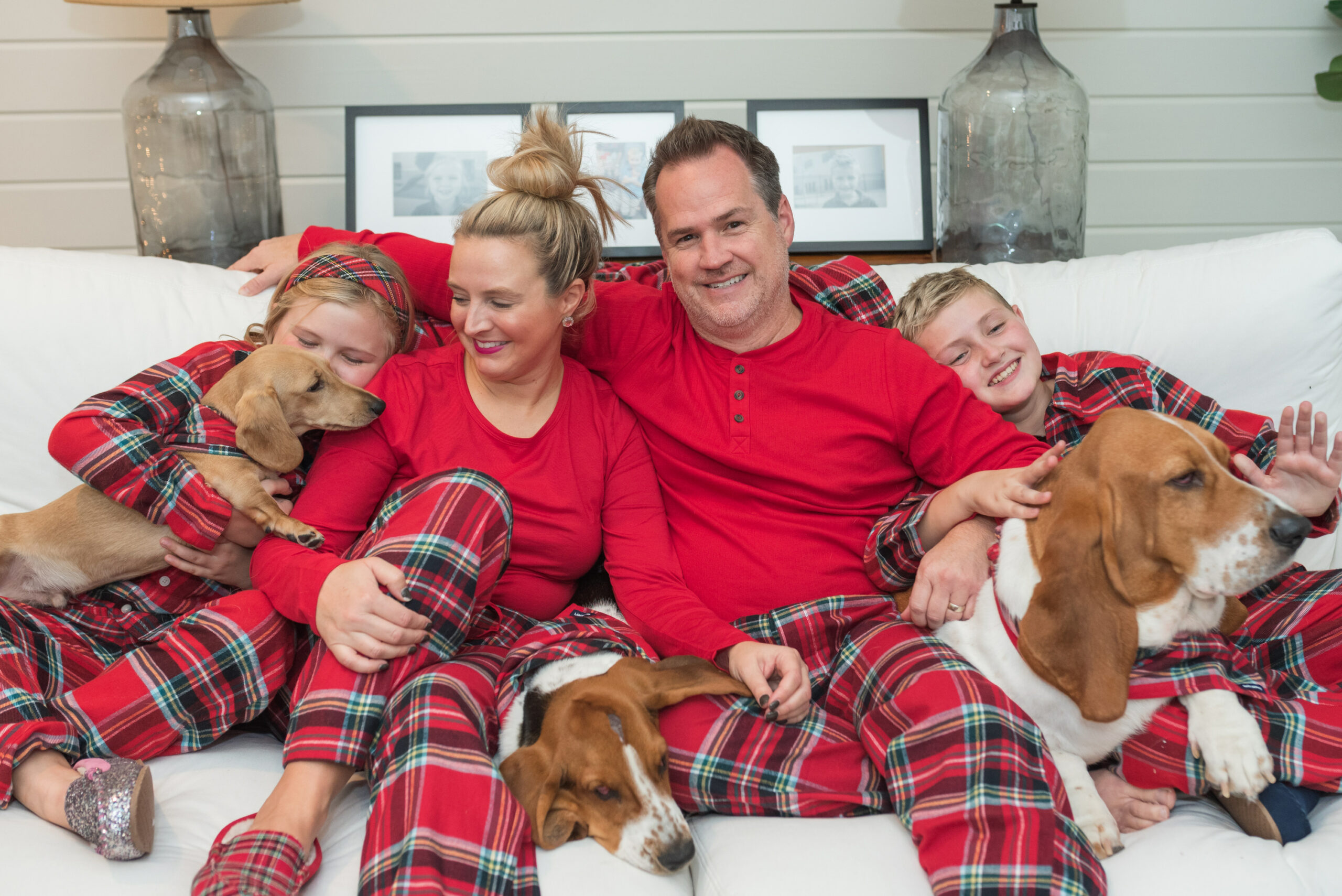 Family Christmas Pajamas by popular Houston fashion blog, Fancy Ashley: image of a family sitting on a white couch with their three dogs and wearing matching red plaid pajamas from Land's End. 