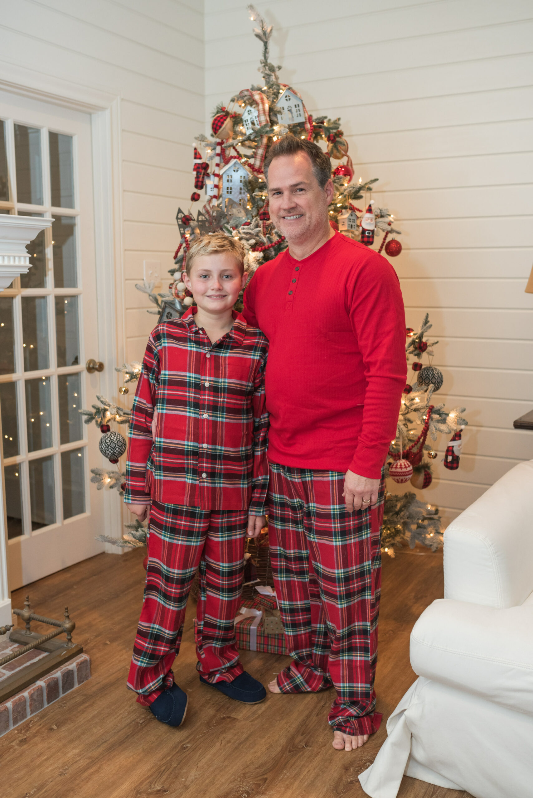 Family Christmas Pajamas by popular Houston fashion blog, Fancy Ashley: image of a dad and his son wearing matching red plaid Land's Ends pajamas and standing in front of a Christmas tree. 