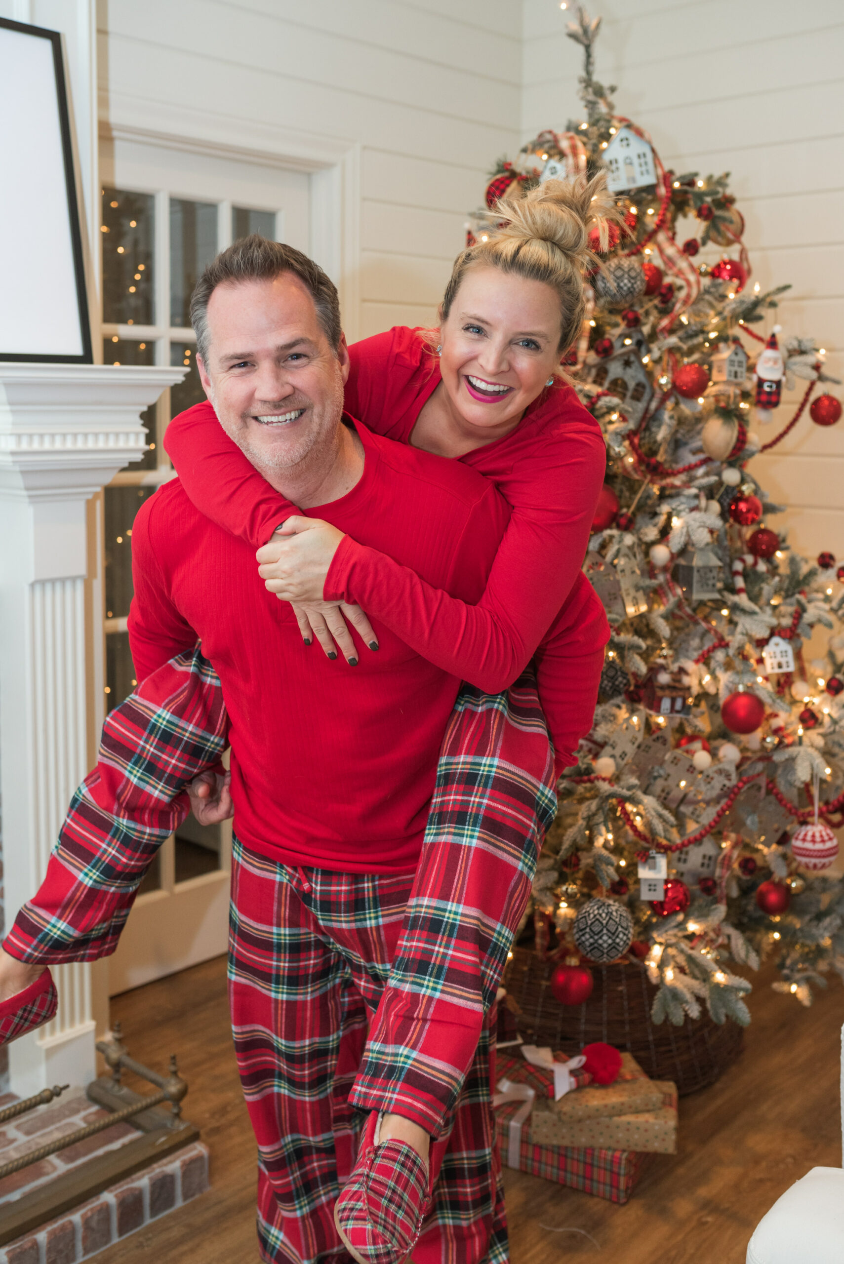 Family Christmas Pajamas by popular Houston fashion blog, Fancy Ashley: image of a husband and wife wearing matching Land's End red plaid pajamas and standing in front of a Christmas tree. 