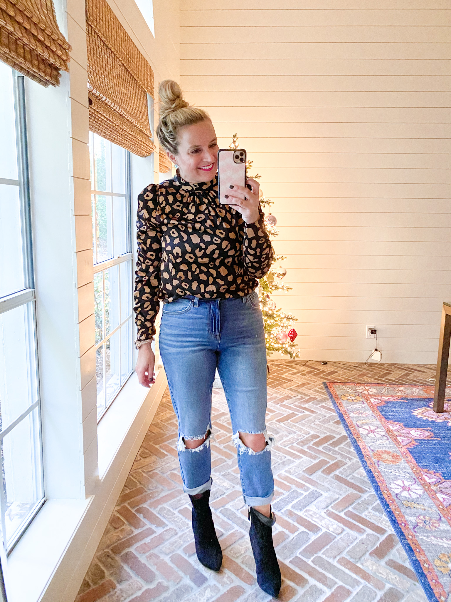 November Outfits by popular Houston fashion blog, Fancy Ashley: image of a woman wearing a leopard print mock neck blouse, distressed denim and black ankle boots. 