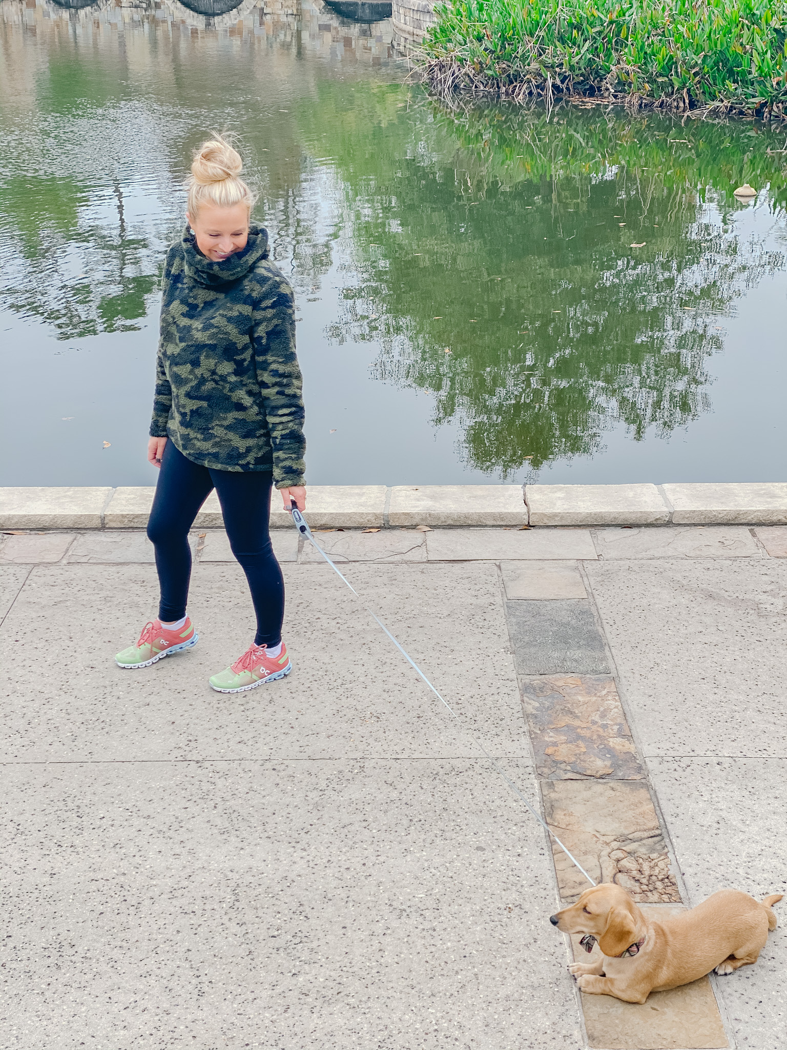 On Cloud Running Shoes by popular Houston fashion blog, Fancy Ashley: image of a woman walking her dog and wearing Shoes Cloudflow Running Shoes, Zella leggings, Zella camo fleece pullover, and Quay Australia sunglasses. 