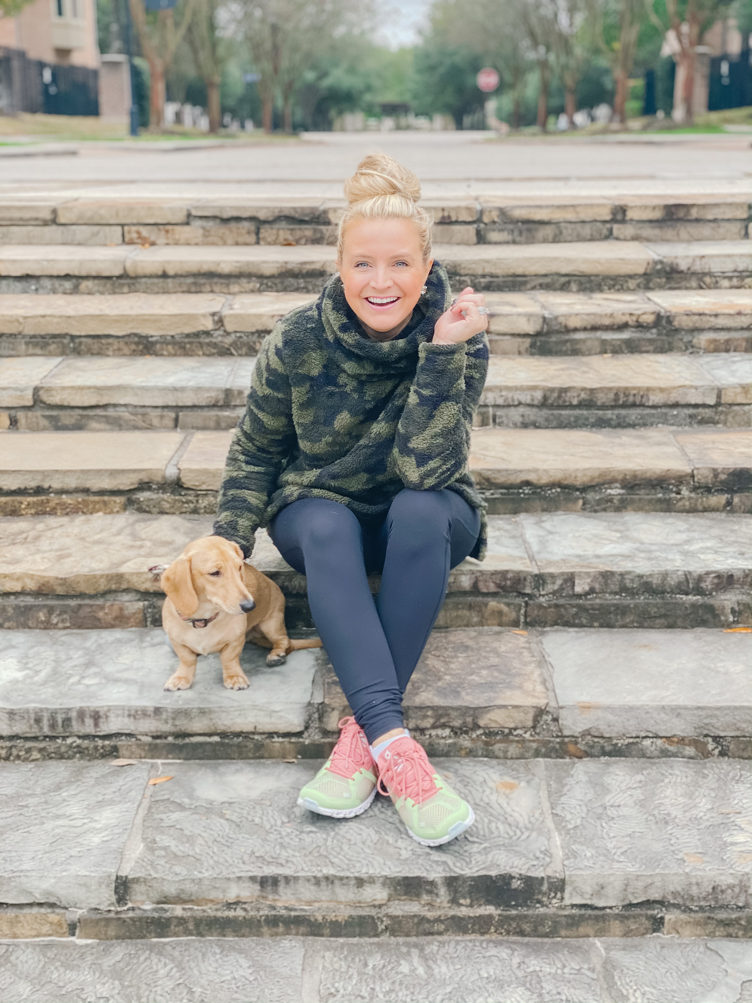 On Cloud Running Shoes by popular Houston fashion blog, Fancy Ashley: image of a woman sitting on some stone steps with her dog and wearing Shoes Cloudflow Running Shoes, Zella leggings, Zella camo fleece pullover, and Quay Australia sunglasses. 