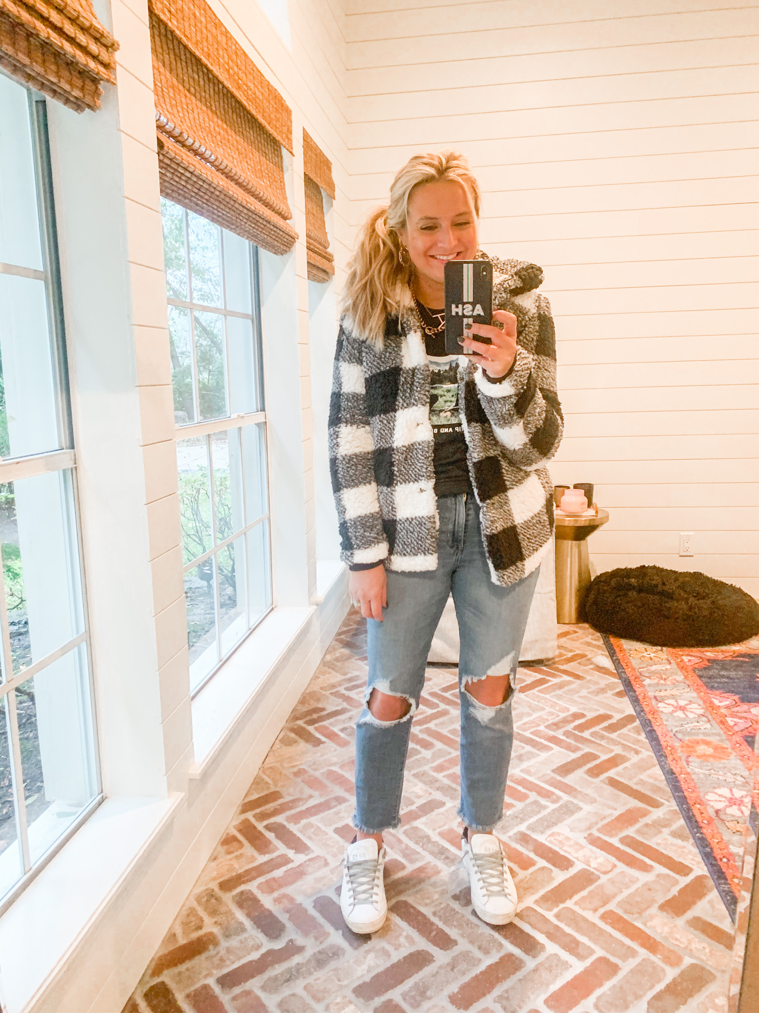 Cute Fall Outfits by popular Houston fashion blog, Fancy Ashley: image of a woman wearing a black and white buffalo plaid jacket, black t-shirt, distressed jeans, gold hoop earrings, and white sneakers. 