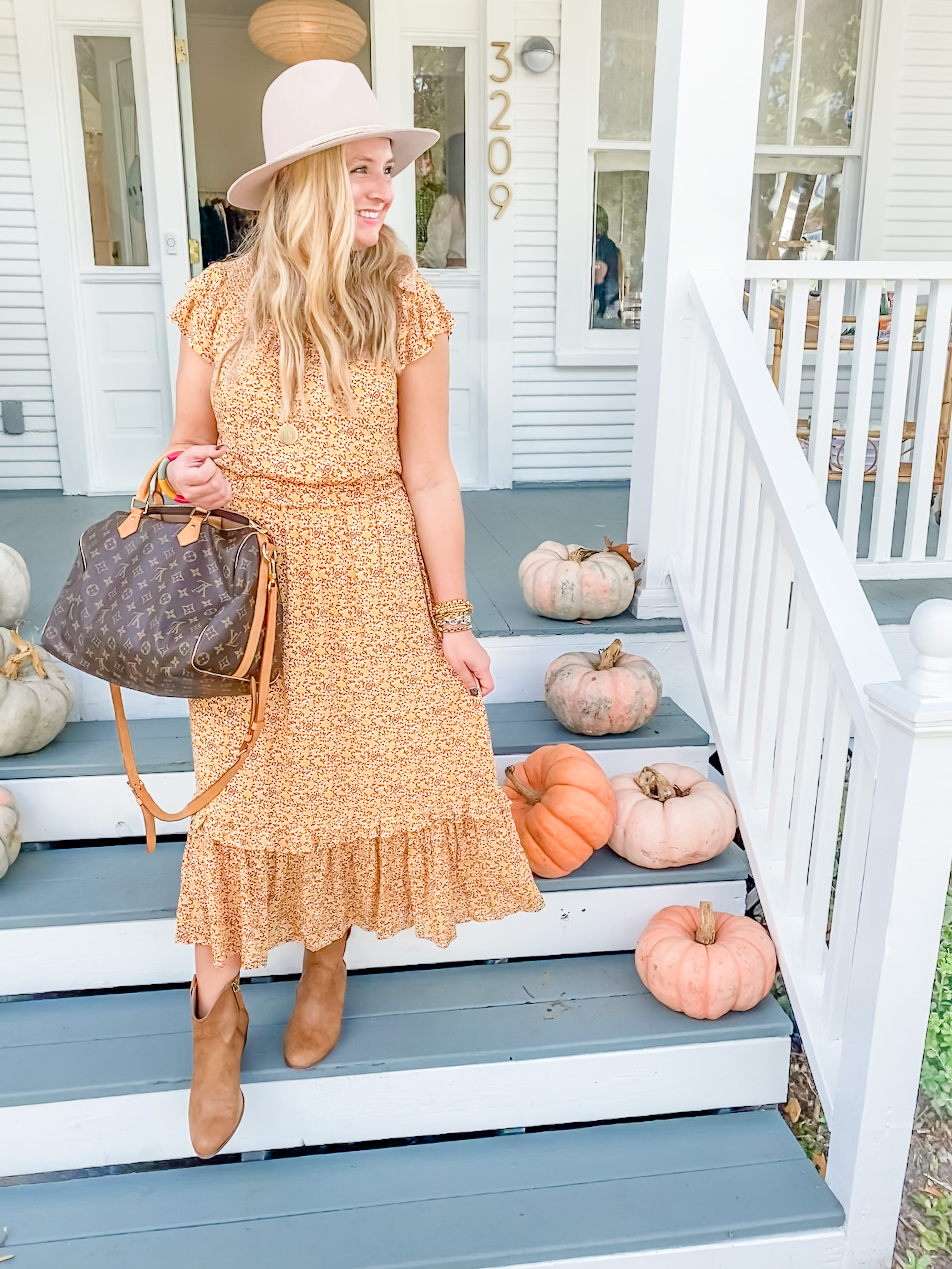 Cute Fall Outfits by popular Houston fashion blog, Fancy Ashley: image of a woman wearing a orange floral print ruffle hem maxi dress, felt hat, tan ankle boots and holding a Louis Vuitton bag. 