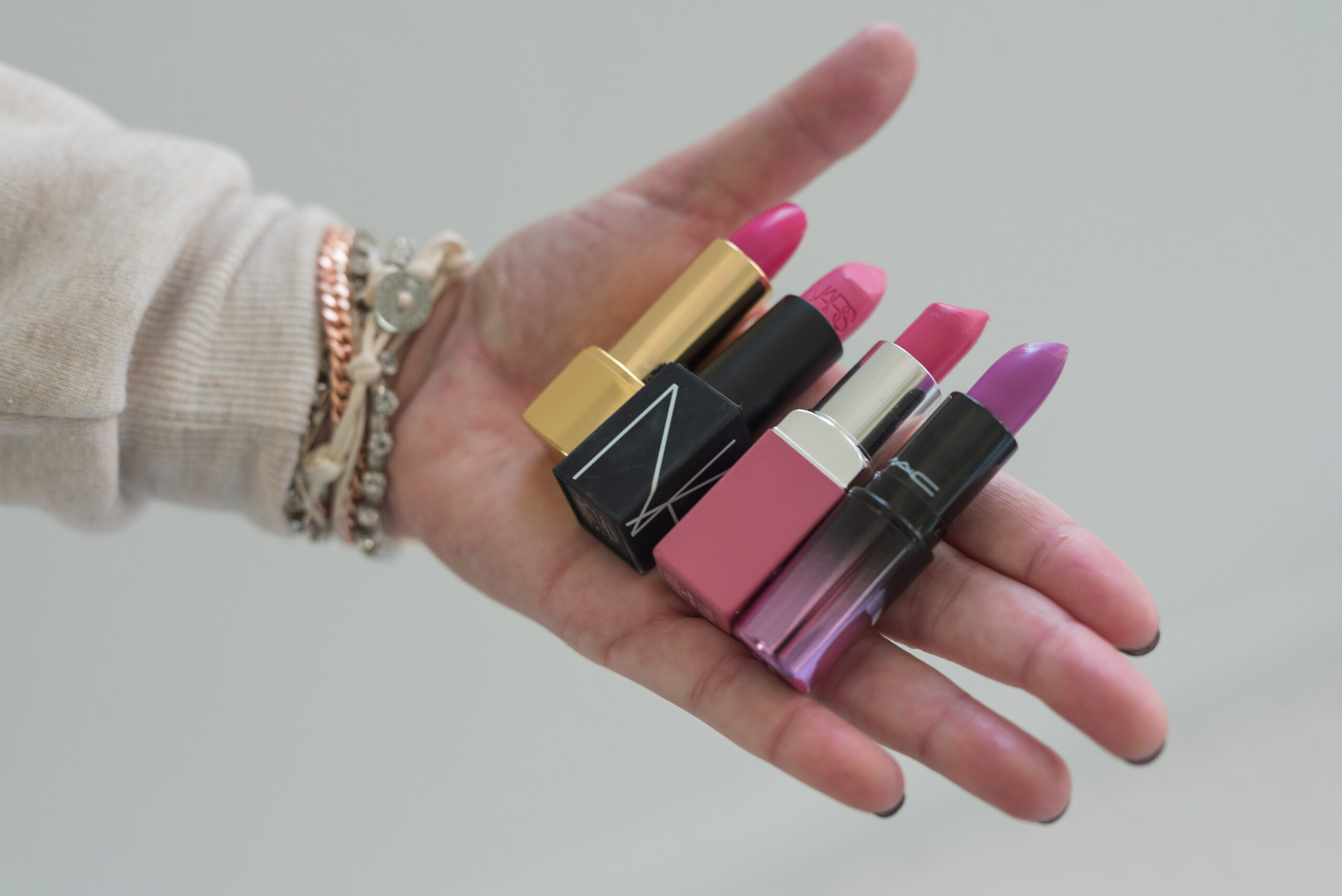Nordstrom Beauty by popular Houston beauty blog, Fancy Ashley: image of a woman holding Nars lipstick, Mac lipstick, Clinique lipstick, and Let Them Eat Cake lipstick. 