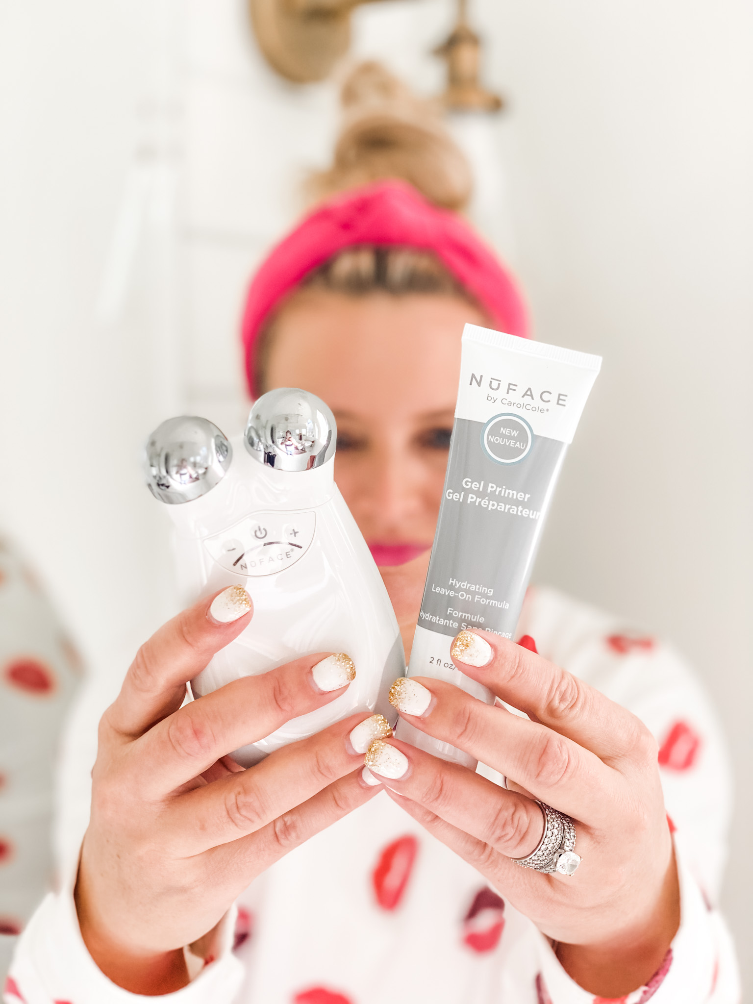 NuFace Trinity by popular Houston beauty blog, Fancy Ashley: image of a woman wearing a lip print pajama set and siting on her bathroom counter while using the NuFace Trinity facial toner. 