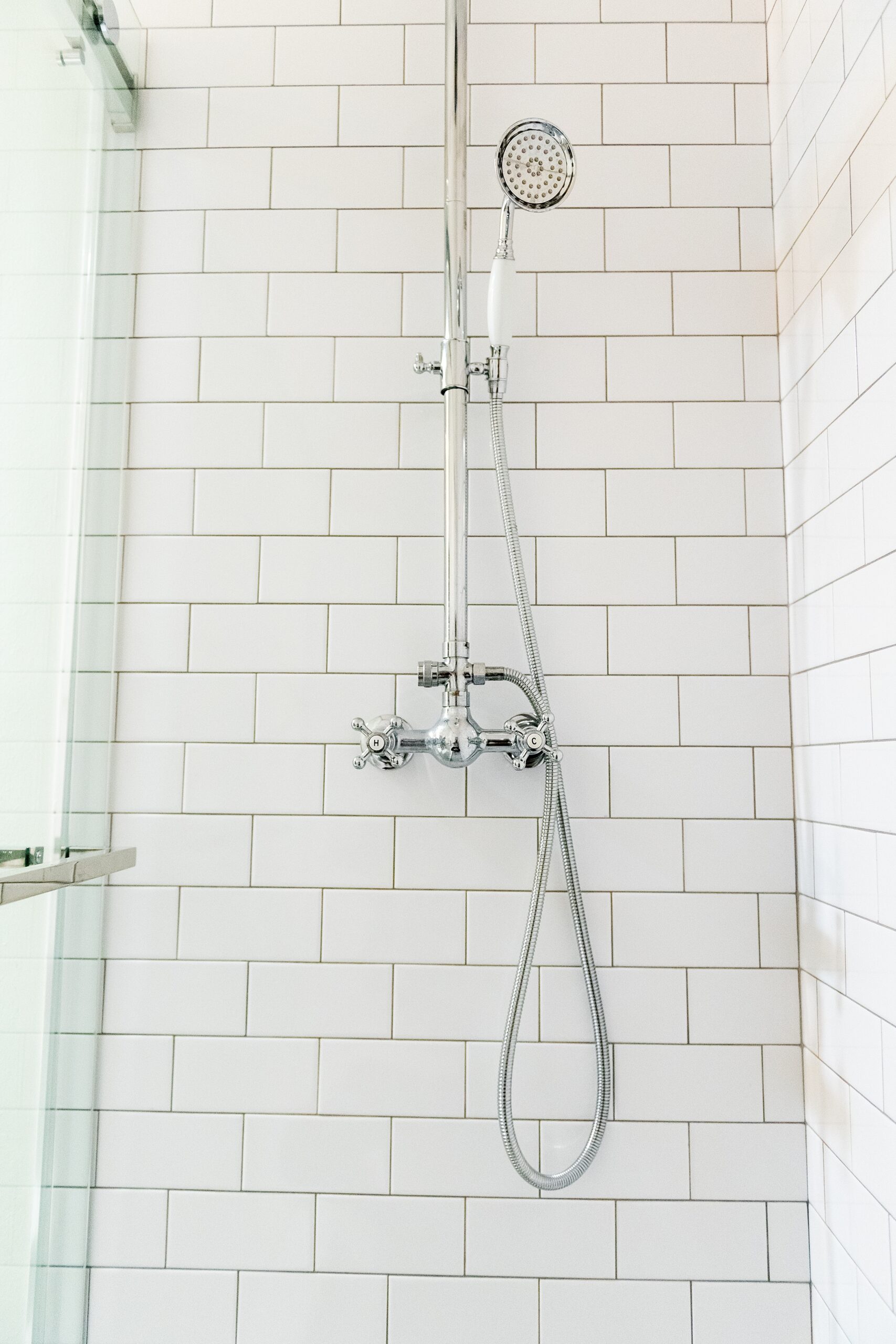 Girls Bathroom by popular Houston life and style blog, Fancy Ashley: image of a bathroom with a walk in shower that has white subway tile and hand held shower head. 