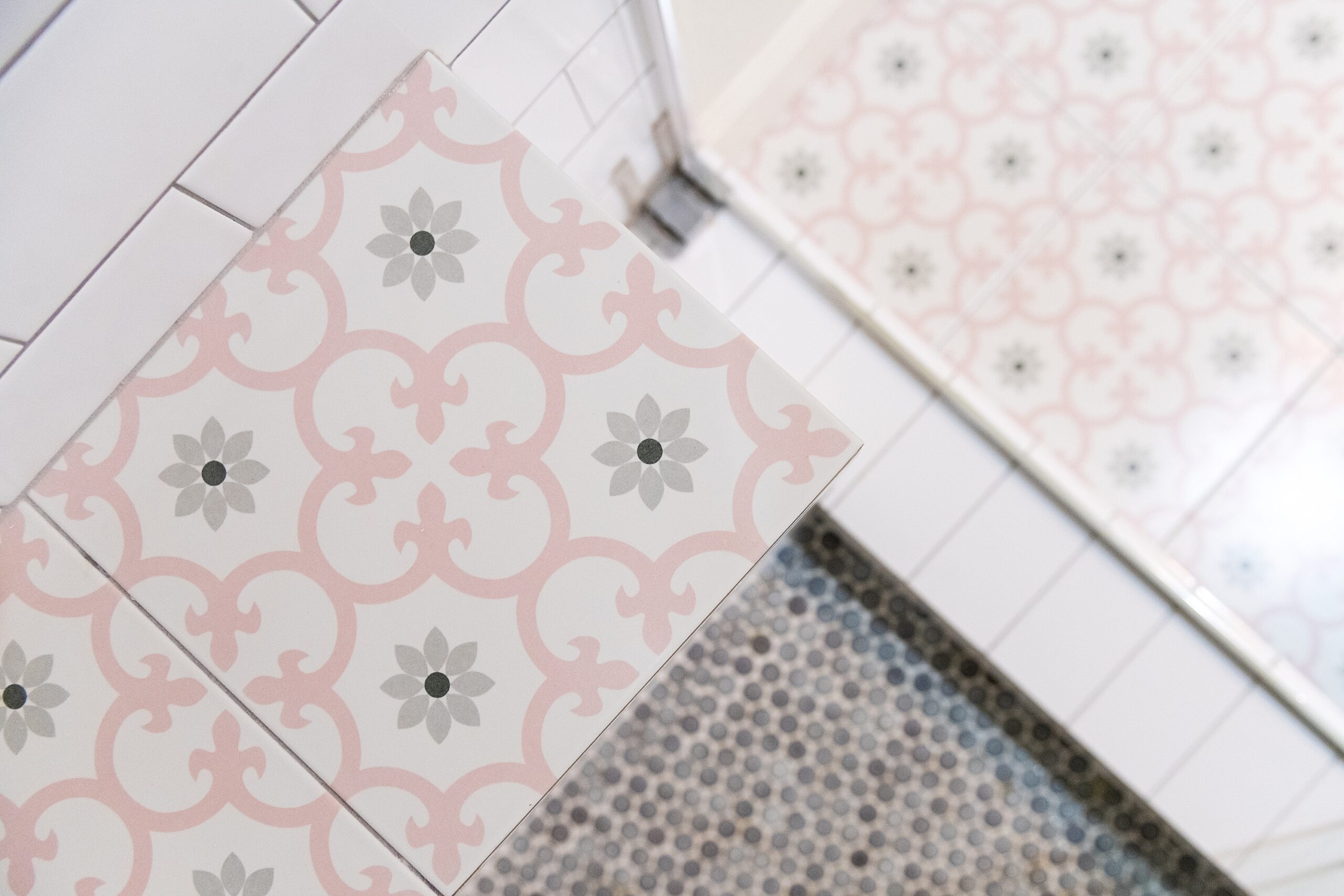 Girls Bathroom by popular Houston life and style blog, Fancy Ashley: image of a bathroom with a walk in shower that has white subway tile, pink and grey tiles, and grey penny tiles. 