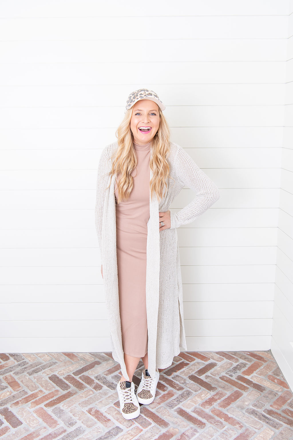 International Women's Day with Gibson by popular Houston fashion blog, Fancy Ashley: image of a woman wearing a Gibson mock neck sleeveless body-con dress with leopard print sneakers, leopard print baseball hat, and white duster cardigan. 