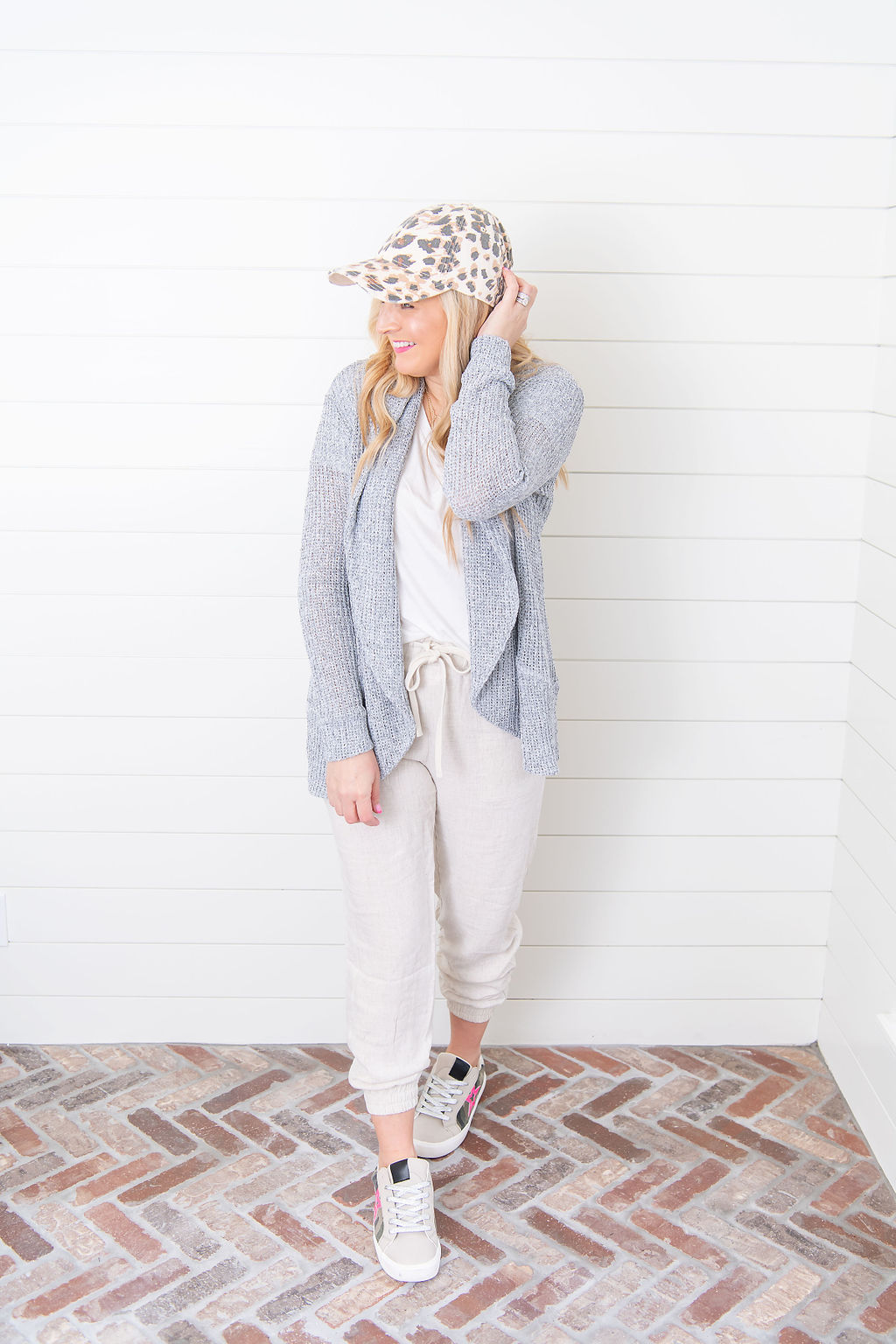 International Women's Day with Gibson by popular Houston fashion blog, Fancy Ashley: image of a woman wearing a Gibson sweater and jogger set with a grey waffle knit sweater, leopard print baseball cap and white sneakers. 