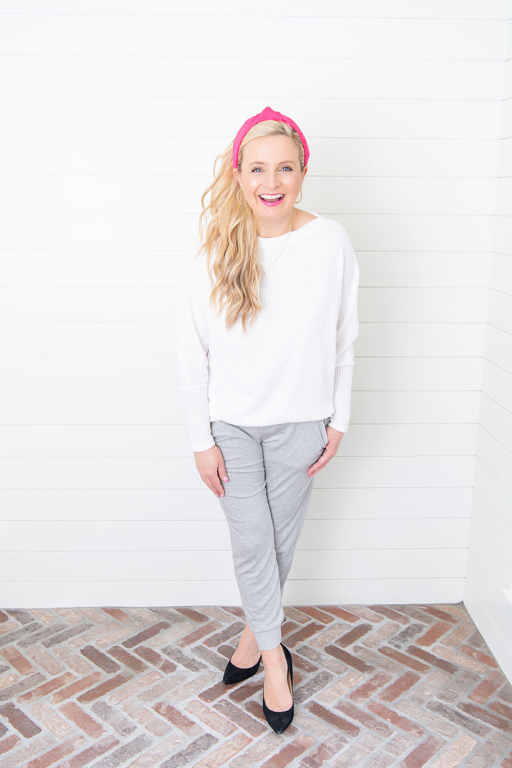 International Women's Day with Gibson by popular Houston fashion blog, Fancy Ashley: image of a woman wearing a Gibson Fancy Ashley sweater with a pair of grey jogger pants, black heels, and pink knot headband. 