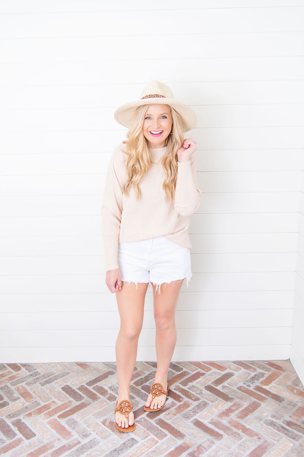 International Women's Day with Gibson by popular Houston fashion blog, Fancy Ashley: image of a woman wearing a Fancy Ashley sweater with a pair of white cut off shorts, brown sandals, and straw hat. 