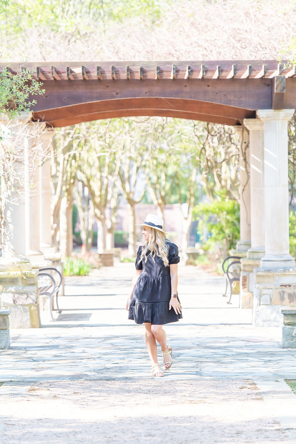 Little Black Dresses by popular Houston fashion blog, The House of Fancy: image of a woman wearing a black baby doll dress, white fedora hat, and studded strap sandals. 