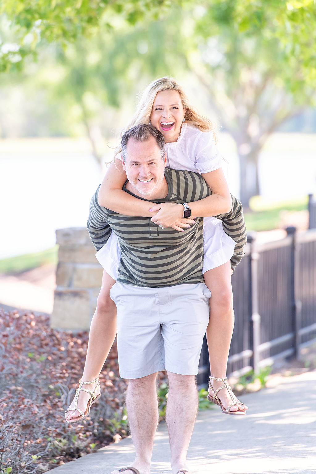 Inspire Others by popular Houston lifestyle blog, The House of Fancy: image of a husband giving his wife piggy back ride and wearing a white dress, green stripe long sleeve henley shirt, grey shorts, brown flip flops, and gold studded strap sandals. 