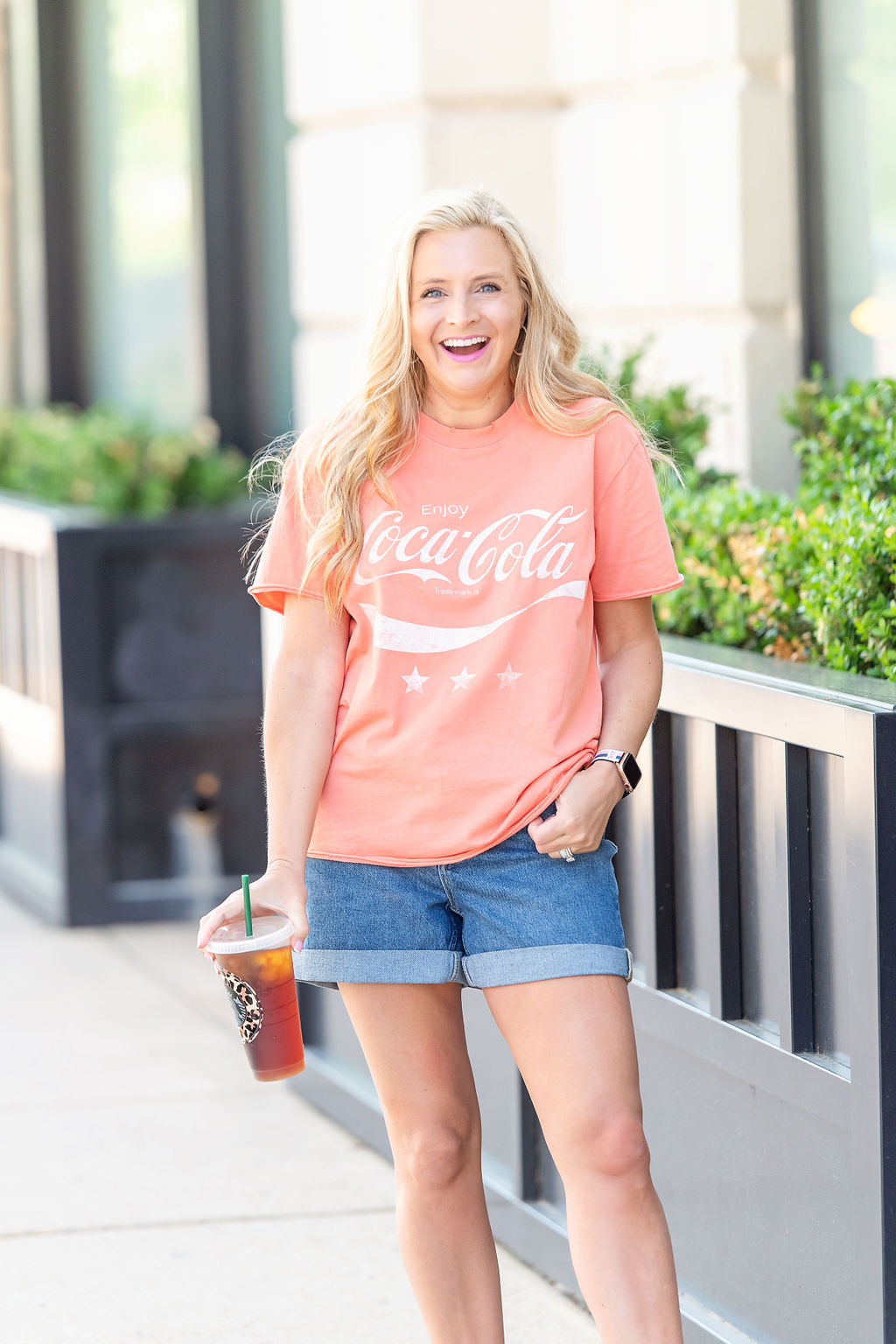 Denim Shorts by popular Houston fashion blog, The House of Fancy: image of a woman standing outside and wearing a Cocoa Cola t-shirt with a pair of denim shorts and studded gold strap sandals. 