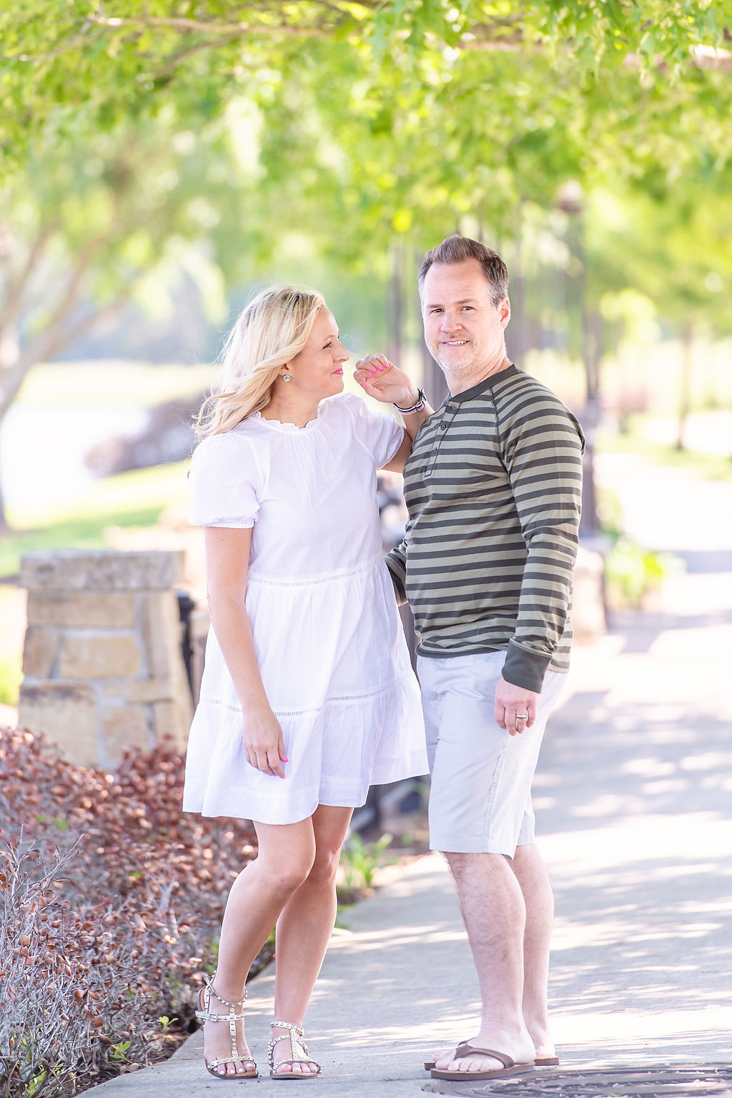 Walmart Summer Fashion by popular Houston fashion blog, The House of Fancy: image of a husband and wife standing together and wearing a white dress, green strip long sleeve shirt and tan shorts. 