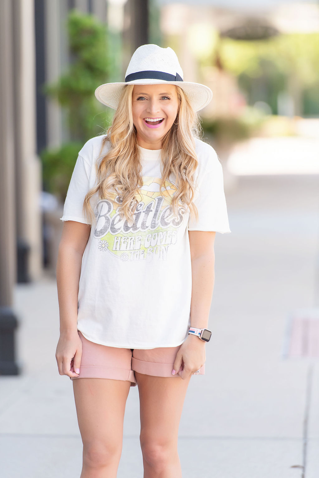 Denim Shorts by popular Houston fashion blog, The House of Fancy: image of a woman standing outside and wearing a The Beatles graphic t-shirt, pink denim shorts, white fedora hat, and studded gold strap sandals. 