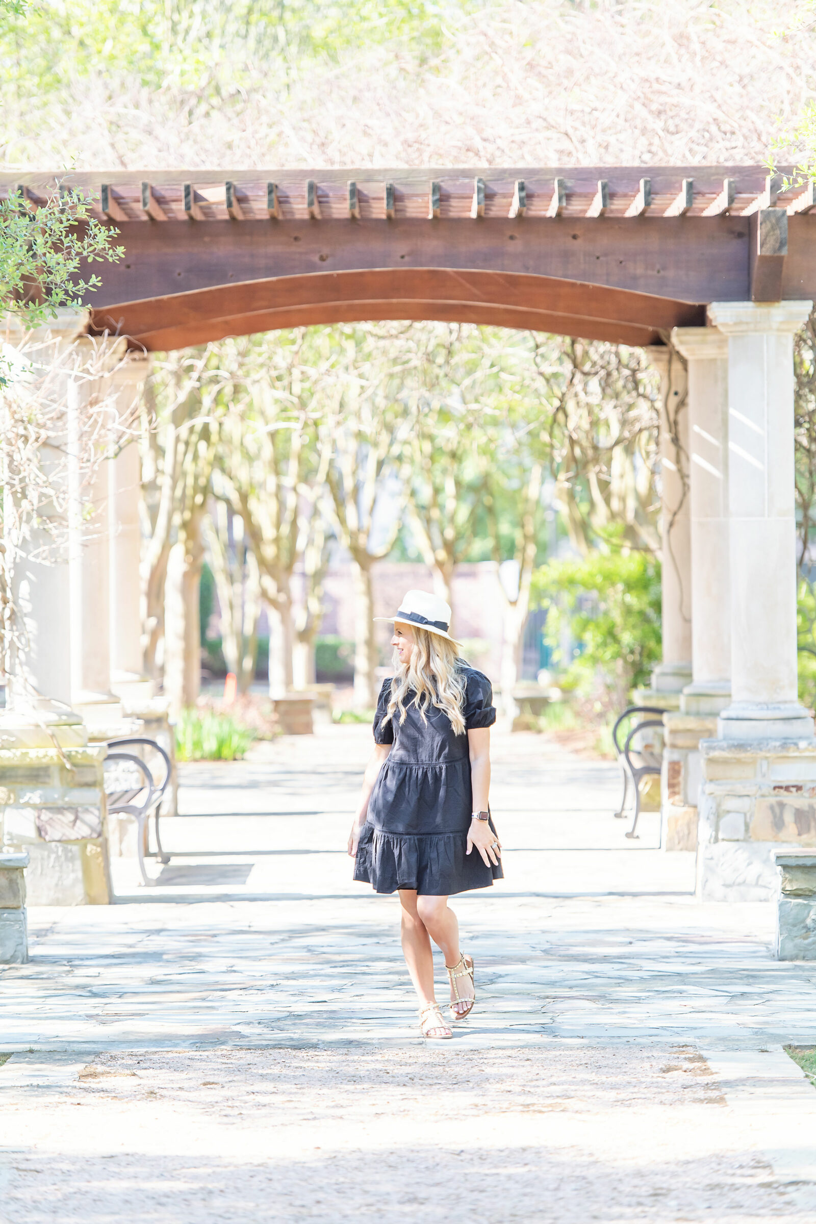 Walmart New Arrivals by popular Houston fashion blog, The House of Fancy: image of a woman standing outside and wearing a black babydoll dress, straw fedora and studded gold strap sandals. 
