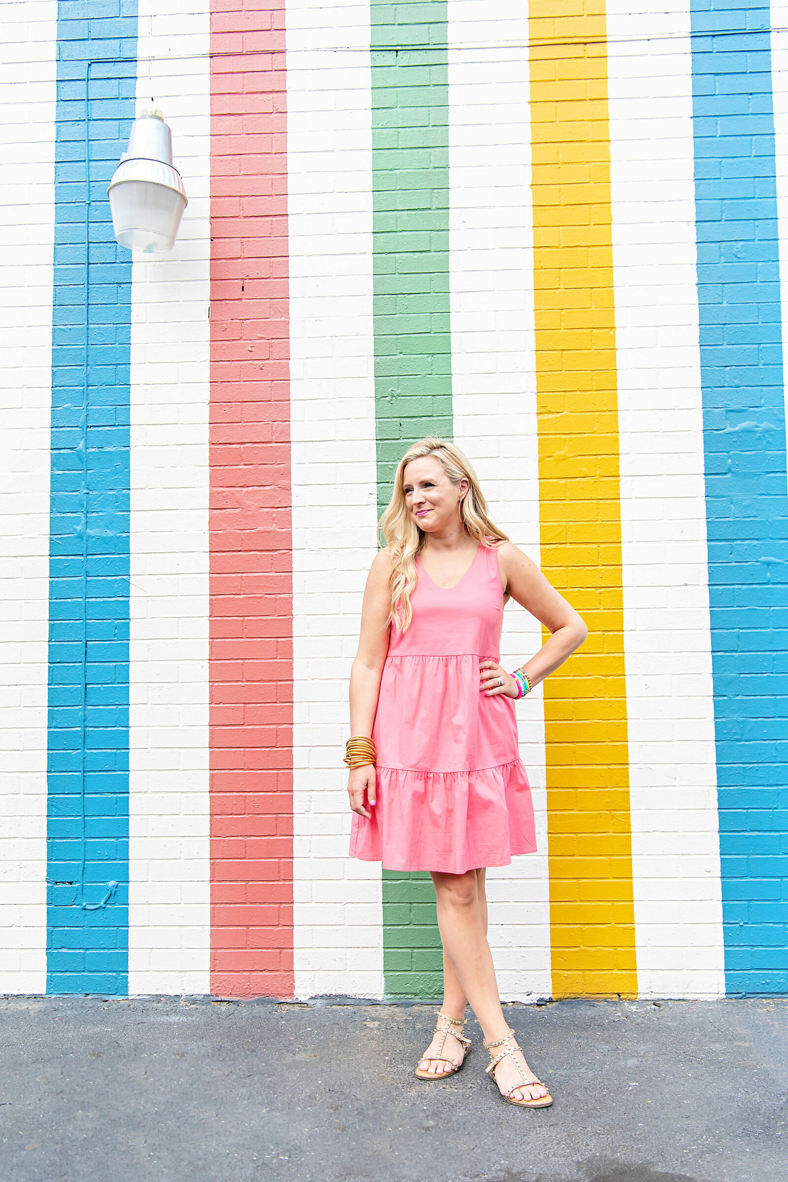 pink graduation dress |. pink graduation dress | Graduation Dress by popular Houston fashion blog, The House of Fancy: image of a woman standing in front of a multi color strip mural and wearing a Gibsonlook Ashley tiered poplin dress, studded gold strap sandals, gold bracelets and colorful stretch bracelets. 