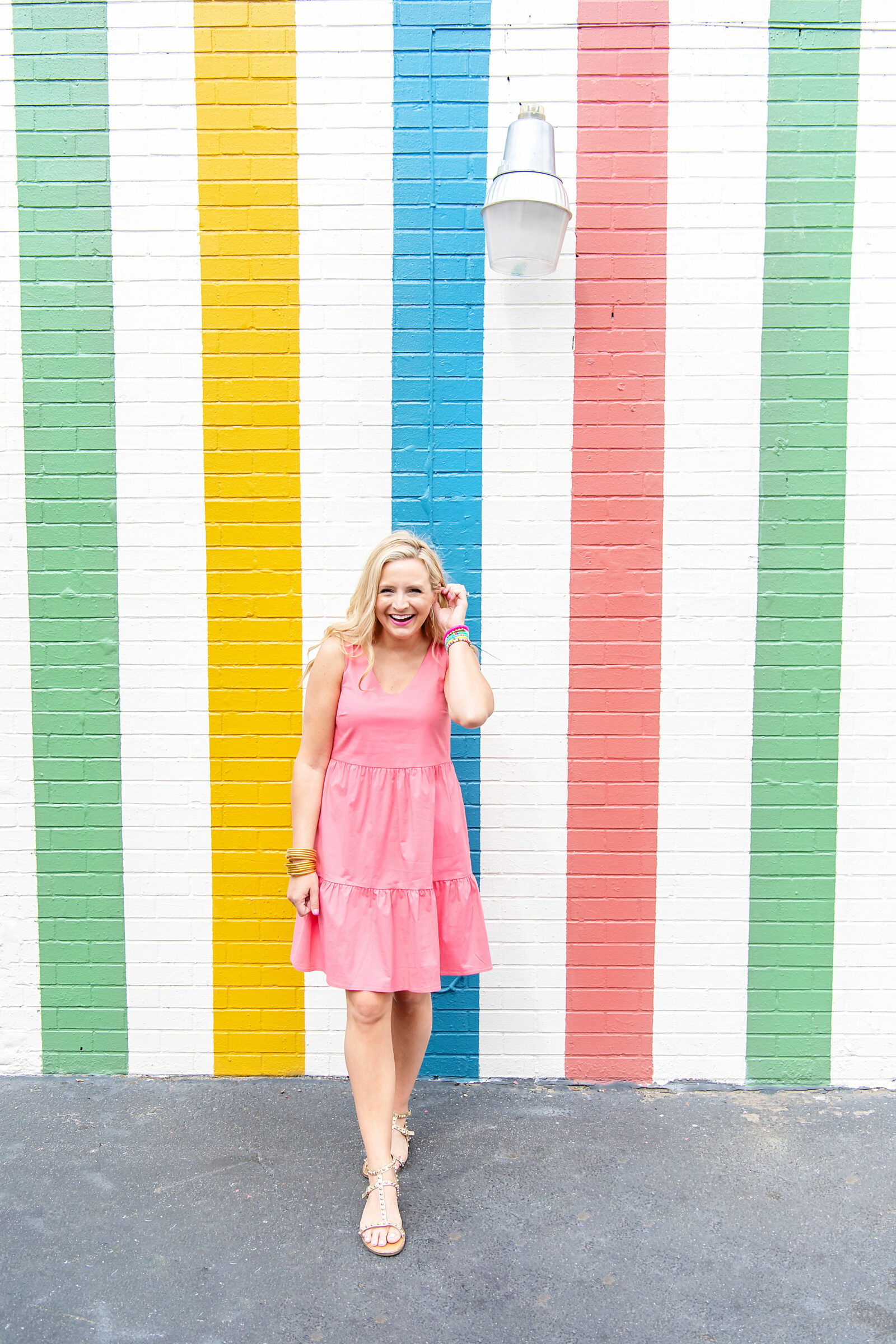 pink graduation dress | Graduation Dress by popular Houston fashion blog, The House of Fancy: image of a woman standing in front of a multi color strip mural and wearing a Gibsonlook Ashley tiered poplin dress, studded gold strap sandals, gold bracelets and colorful stretch bracelets. 