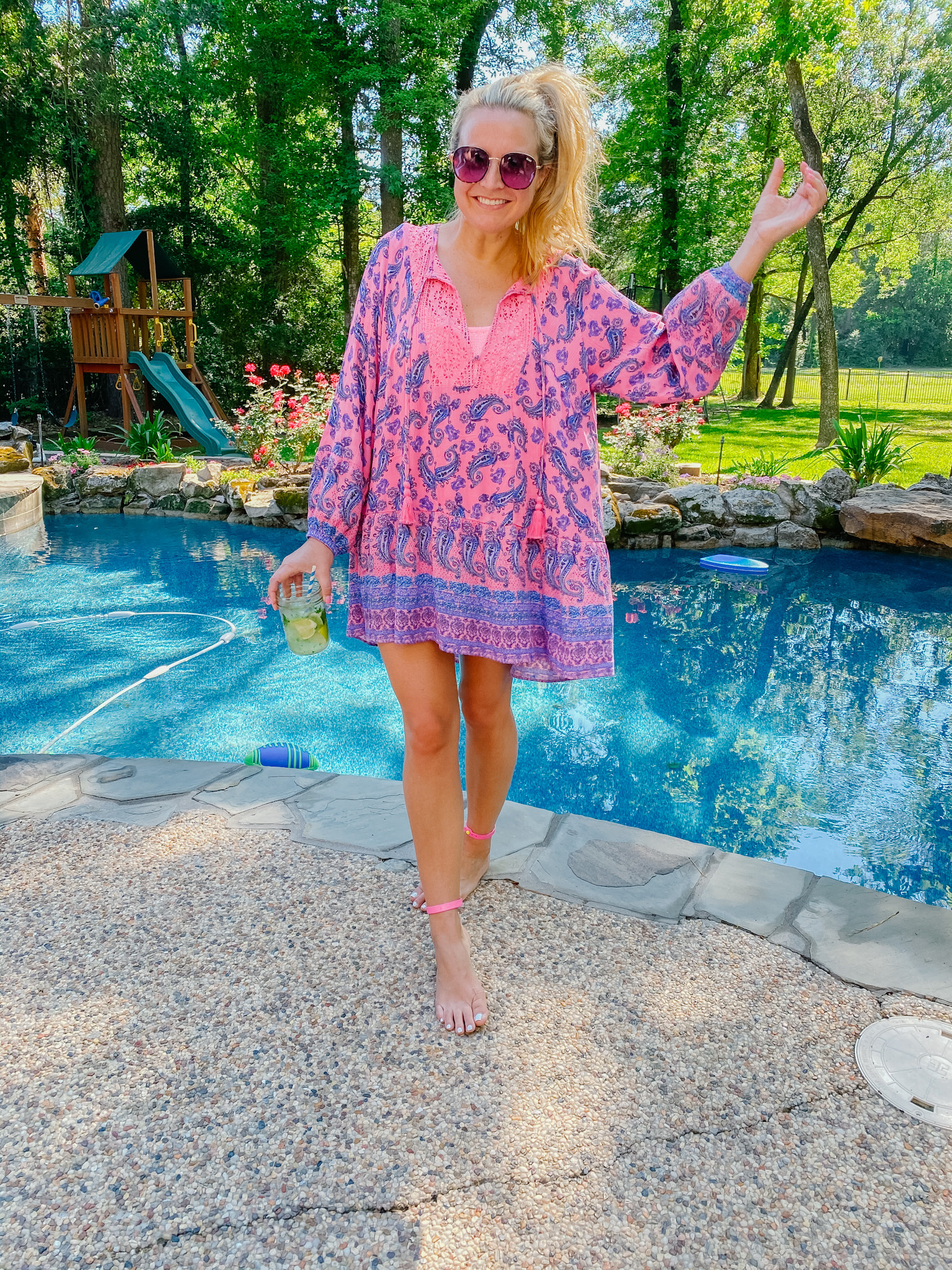 Best Sellers by popular Houston fashion blog, The House of Fancy: image of a woman standing next to a swimming pool and wearing a pink and blue paisley print dress with some oversized sunglasses. 