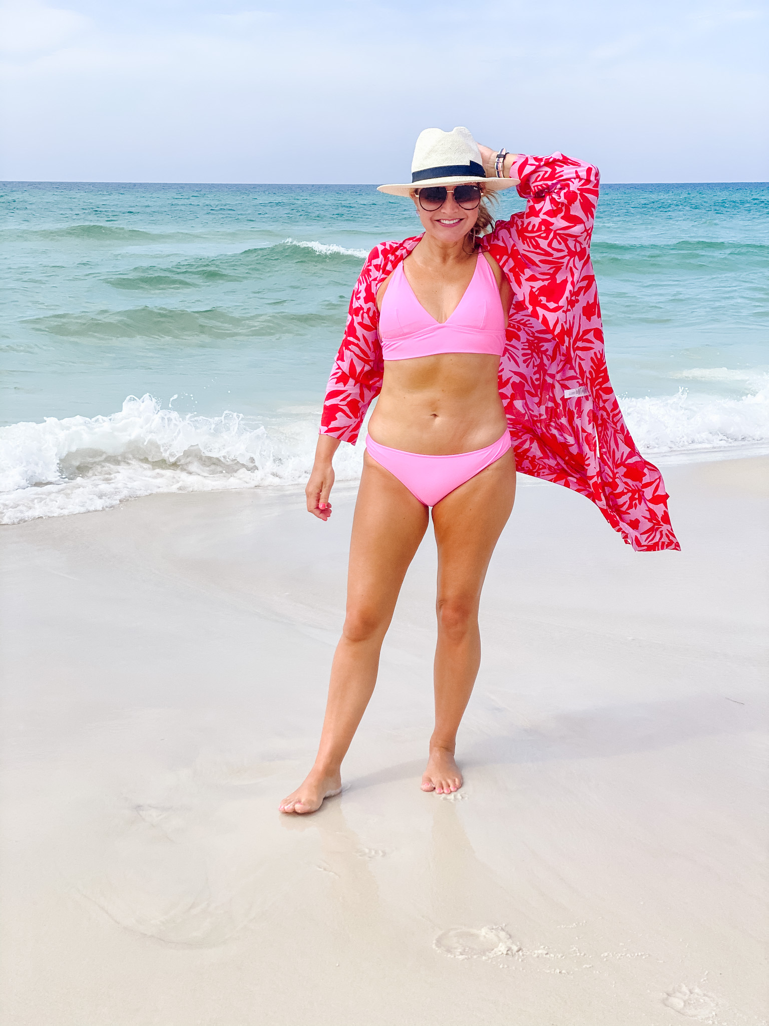 swim packed for my beach vacation | Beach Vacation by popular Houston fashion blog, The House of Fancy: image of a woman standing on a white sand beach next to the ocean and wearing a pink two piece swimsuit, pink and red kimono, sunglasses, and straw fedora hat. 