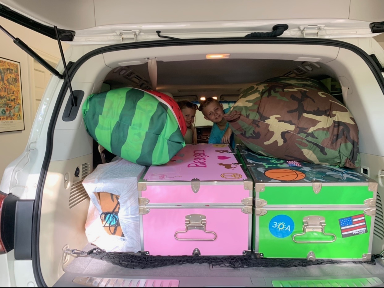 Packing Tips by popular Houston lifestyle blog, The House of Fancy: image of a car filled with a pink and green chest, watermelon print bag and camo print bag in the back of a car. 
