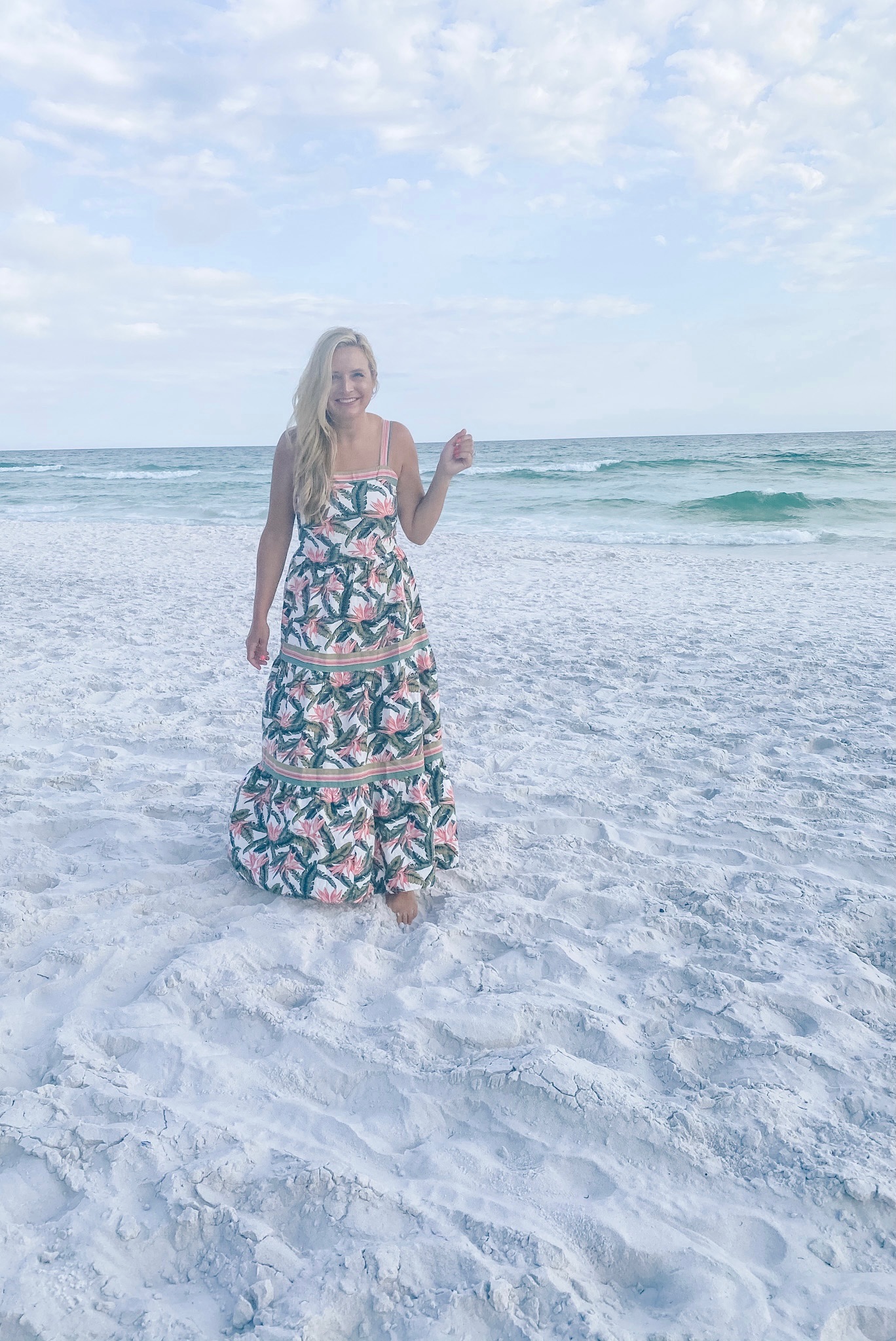 Summer Outfit Ideas by popular Houston fashion blog, The House of Fancy: image of a woman standing on a white sand beach and wearing a pink floral print maxi dress. 