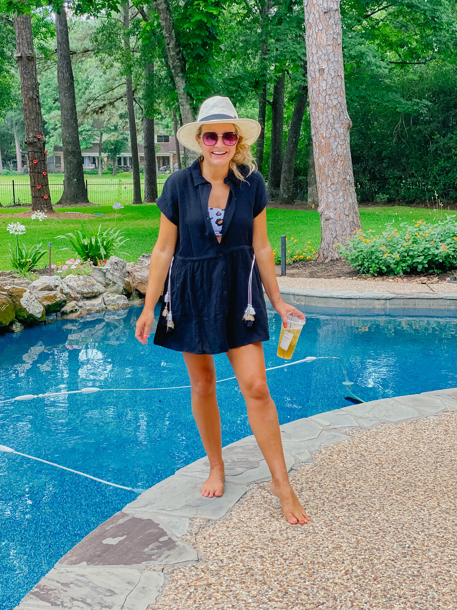 Summer Clothing from Gibson Look by popular Houston fashion blog, The House of Fancy: image of a woman standing outside by a swimming pool and wearing a blue button front tie waist dress with a leopard print swimsuit and straw fedora hat. 