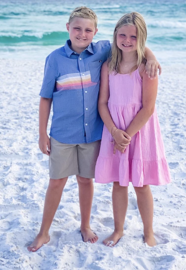 Best Sellers by popular Houston fashion blog, The House of Fancy: image of a young boy and girl standing together on a white sand beach and wearing a pink tiered strap dress, tan shorts, and blue button up shirt with rainbow stripe detail. 
